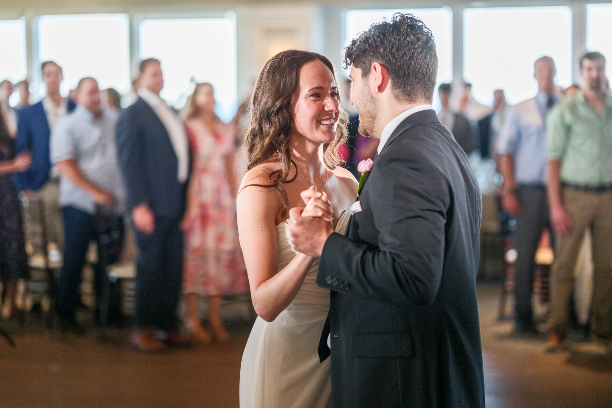 Bride and groom smiling during their first dance at a Blue Ocean Event Center wedding reception.