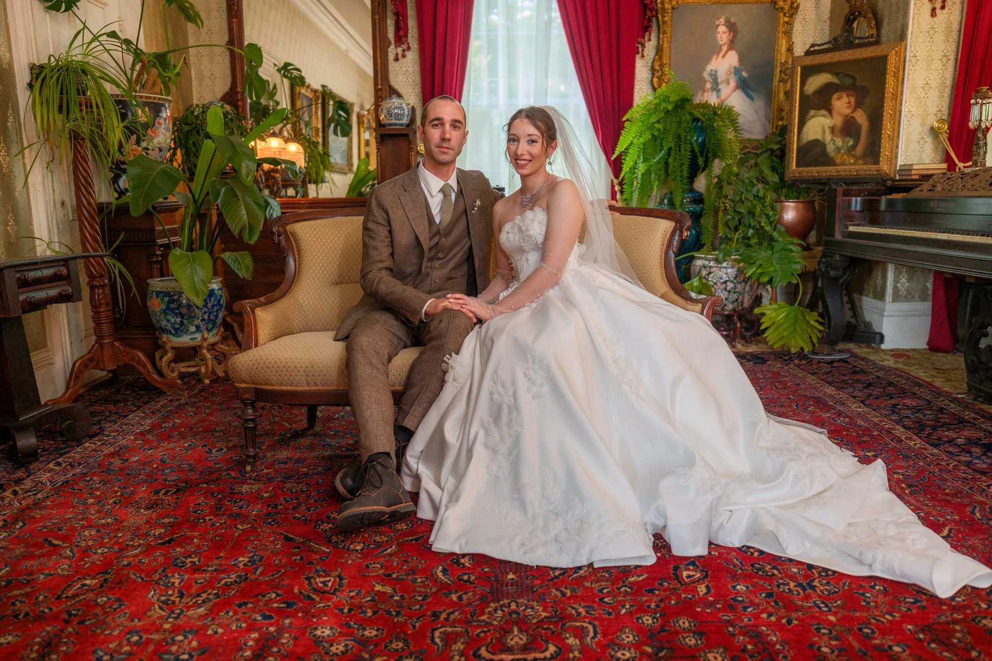 Bride and groom seated together in a richly decorated mansion parlor