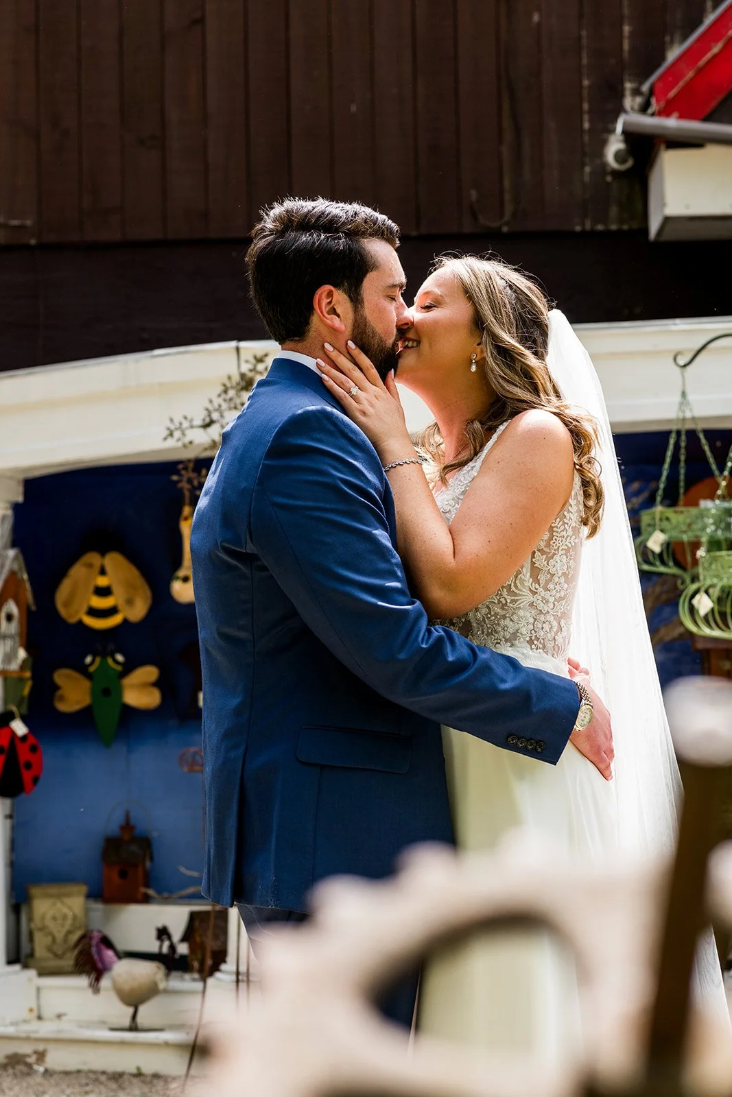 A newlywed couple sharing a kiss during their wedding, with the bride touching the groom's face and both dressed in formal wedding attire.
