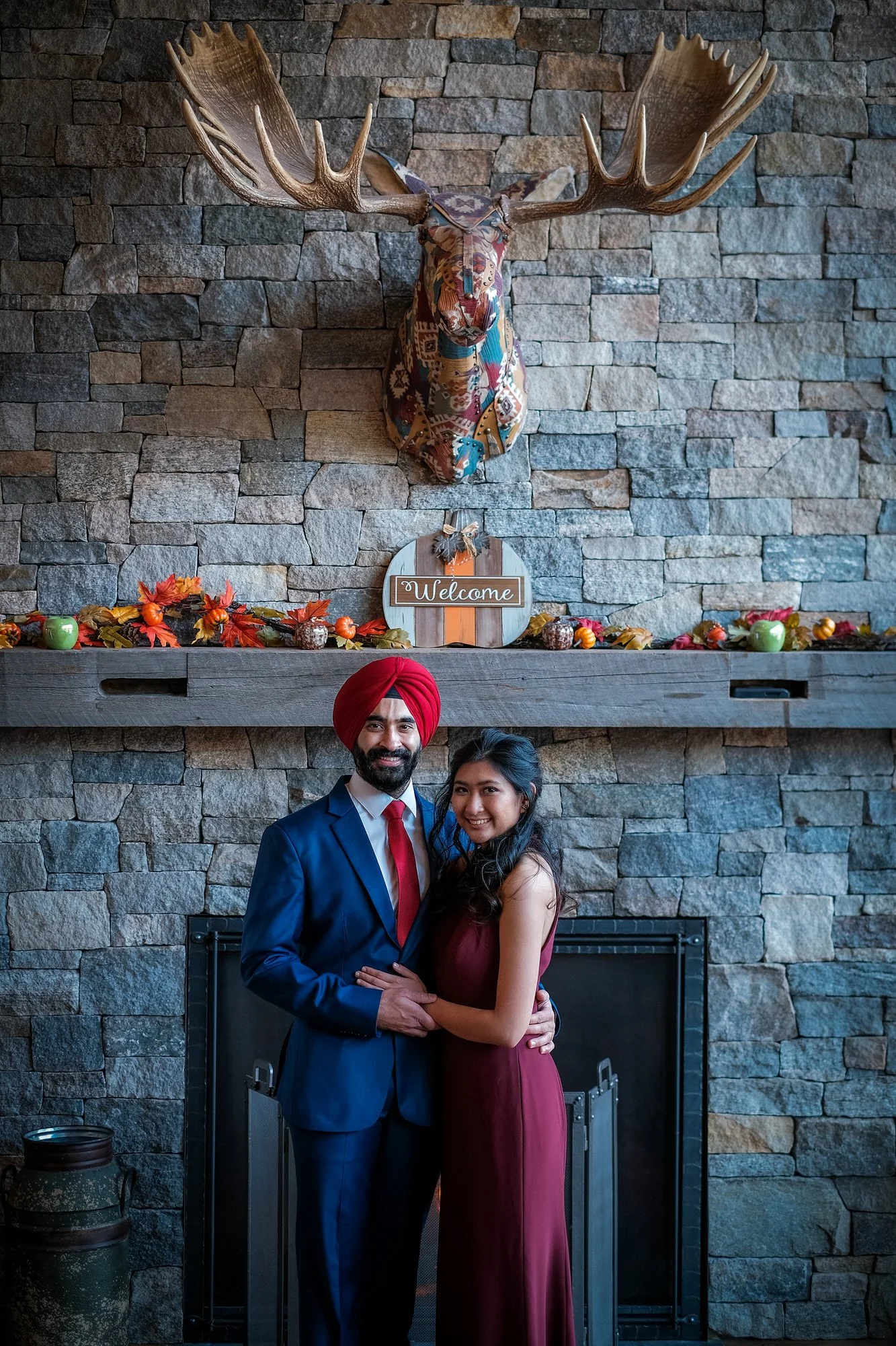 Couple posing together in front of a rustic stone fireplace with moose mount at the Glen House near Mt. Washington during their winter elopement