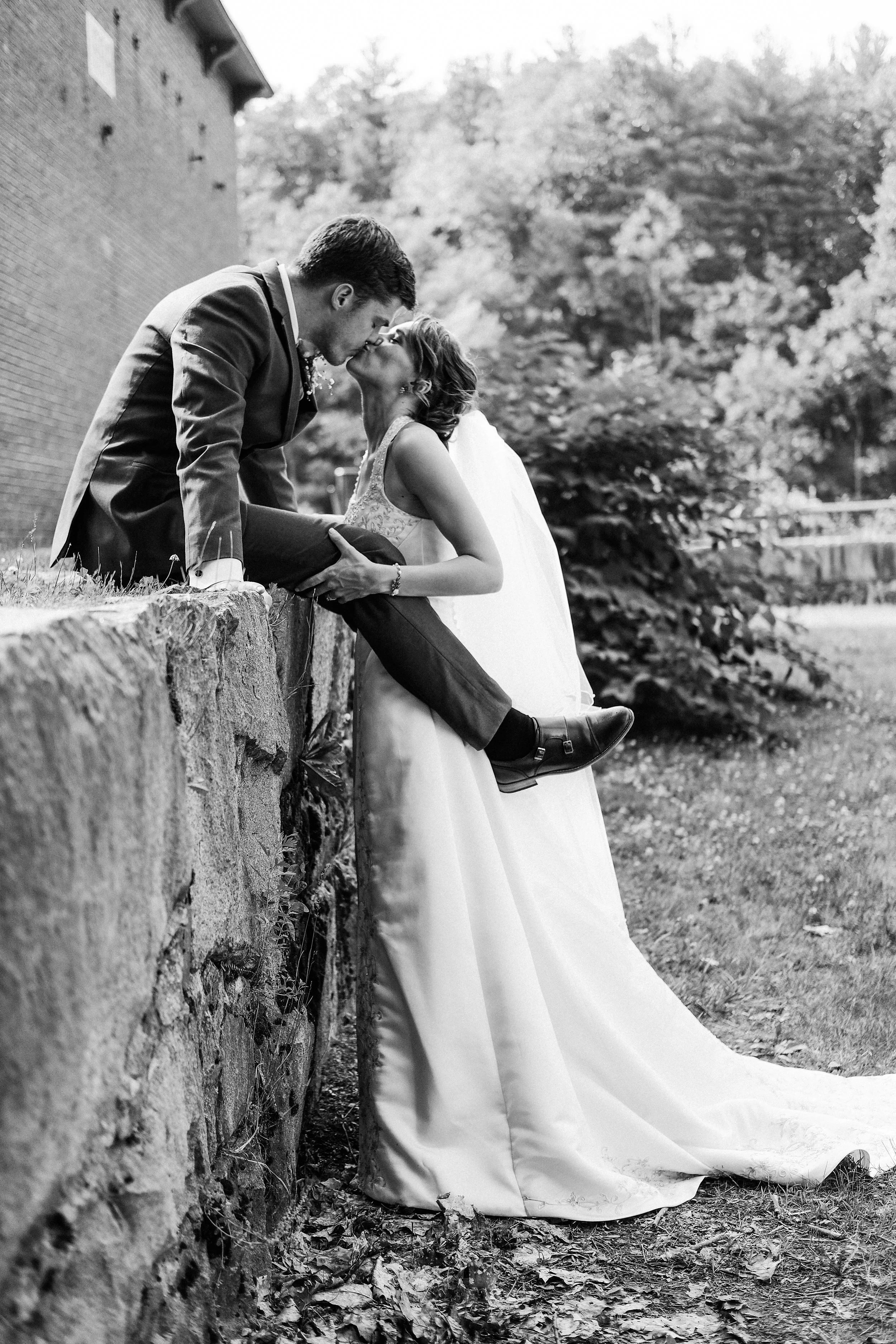 boston-area-wedding-couple-kiss-stone-wall-black-and-white.jpg
