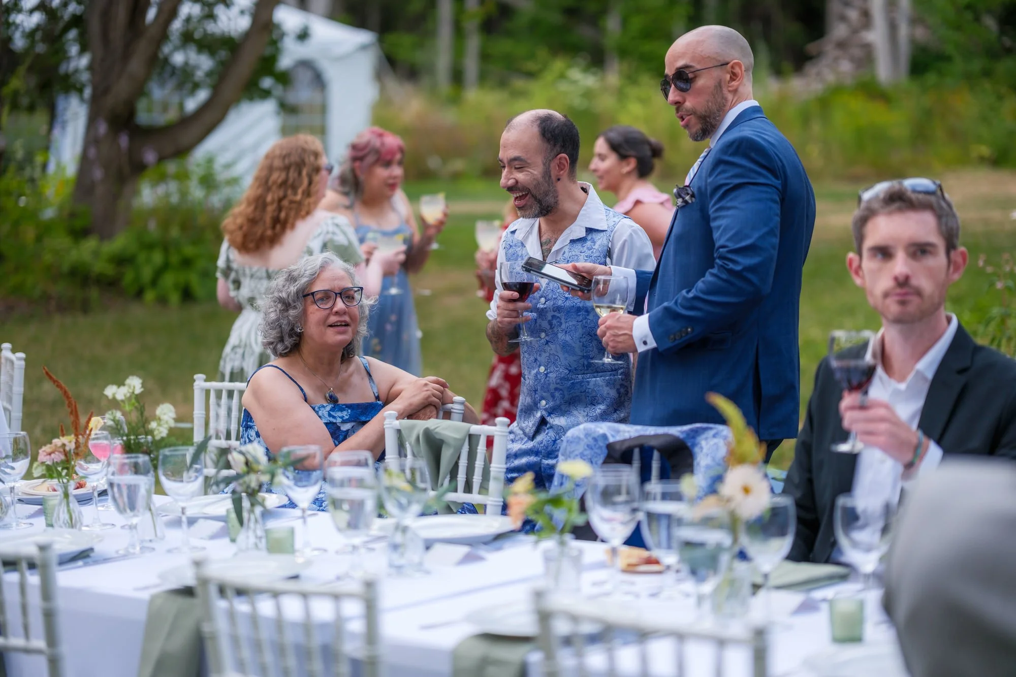Guests seated at outdoor reception tables under the trees