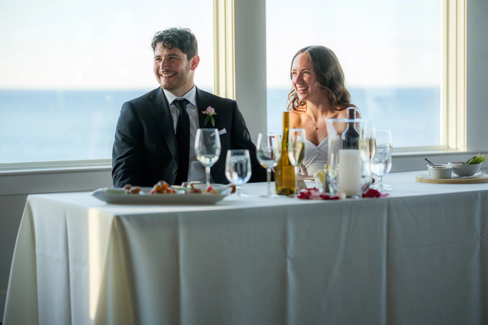 Bride and groom seated at a sweetheart table with ocean views at Blue Ocean Event Center.