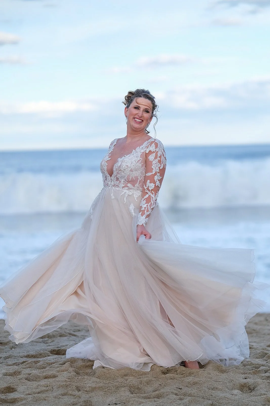 Bride spinning her flowing wedding gown on Salisbury Beach outside Blue Ocean Event Center at dusk