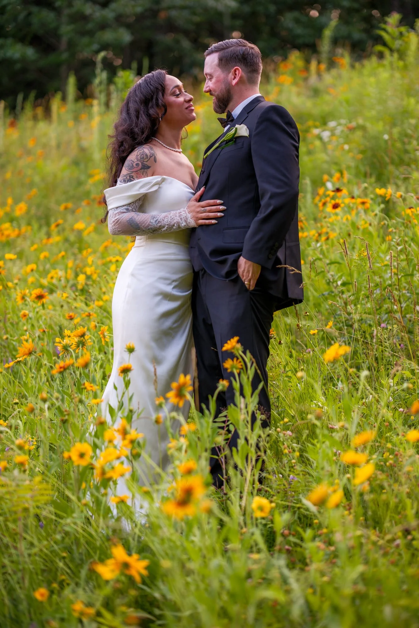 Bride and groom standing among yellow wildflowers at Hyla Brook Estate