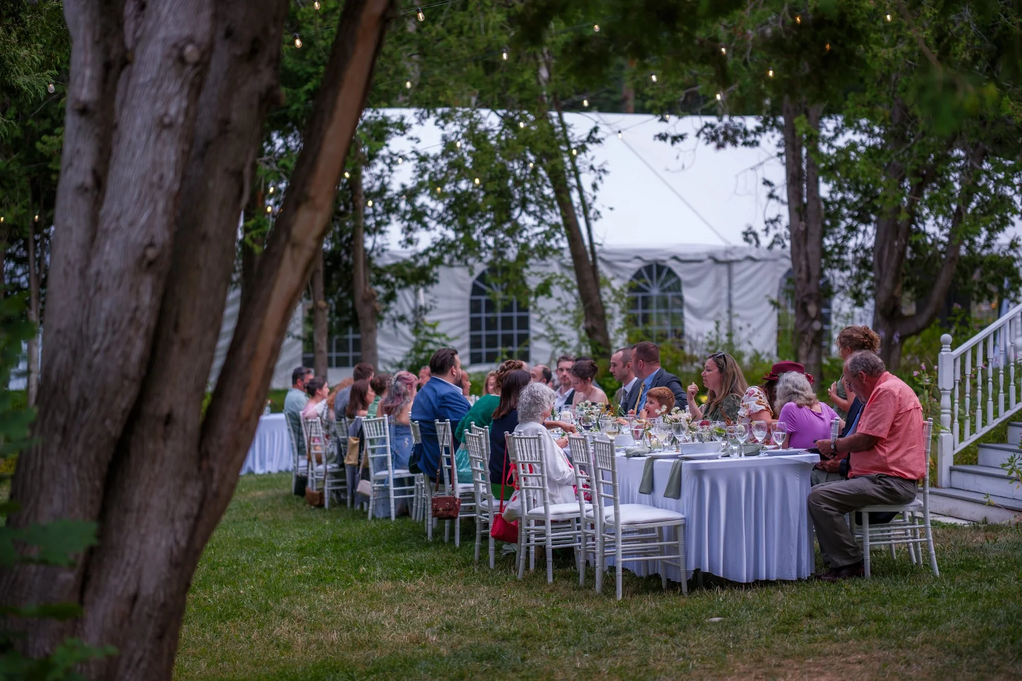 Wedding guests dining at round tables under trees