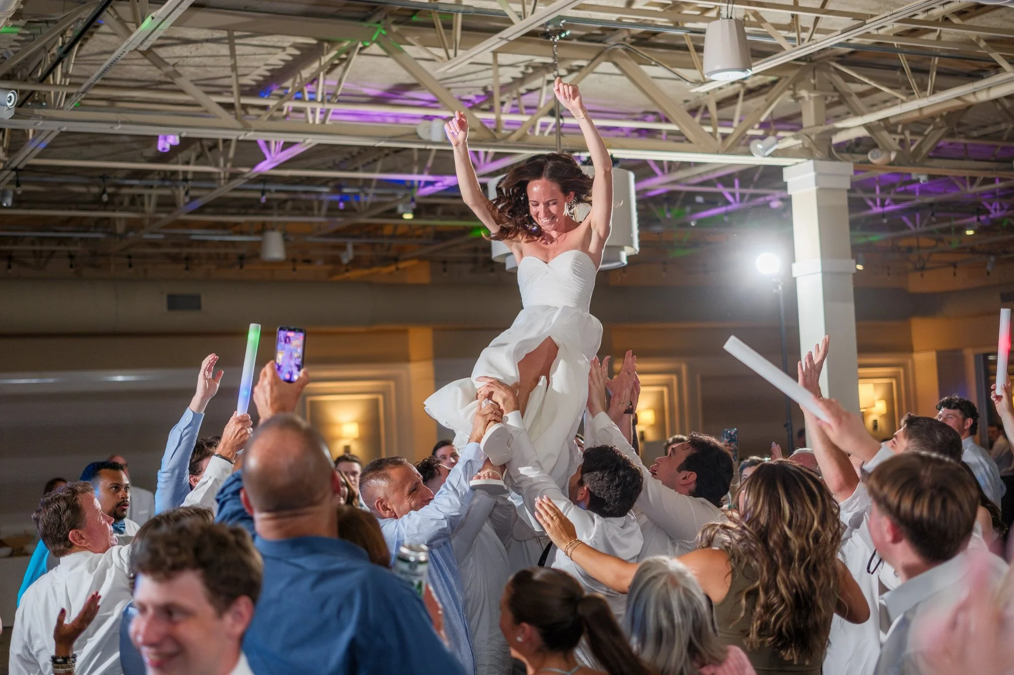 Bride lifted in a chair during a joyful hora dance at Blue Ocean Event Center.