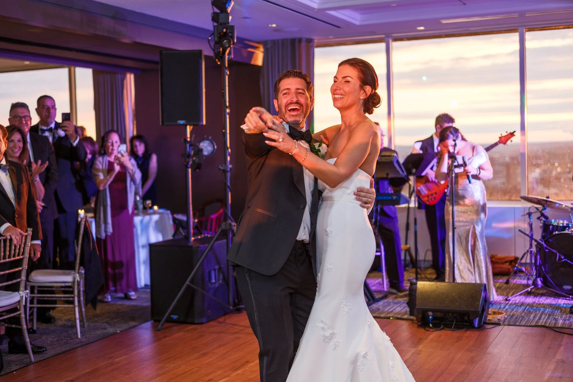 Bride and groom laughing together during their first dance at the UMass Club Boston reception at sunset