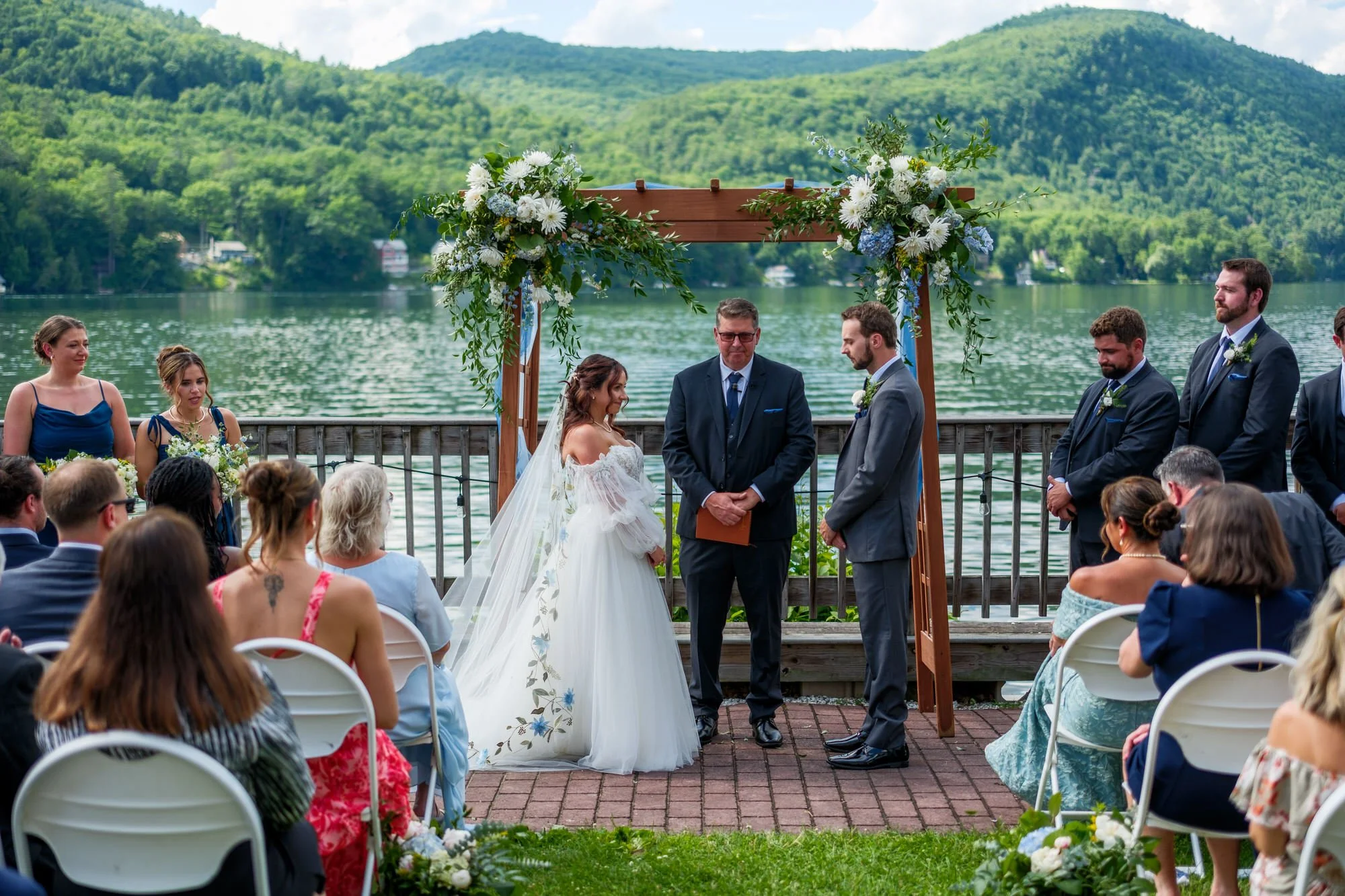 Couple stands beneath floral arbor for Lake Morey Resort wedding ceremony