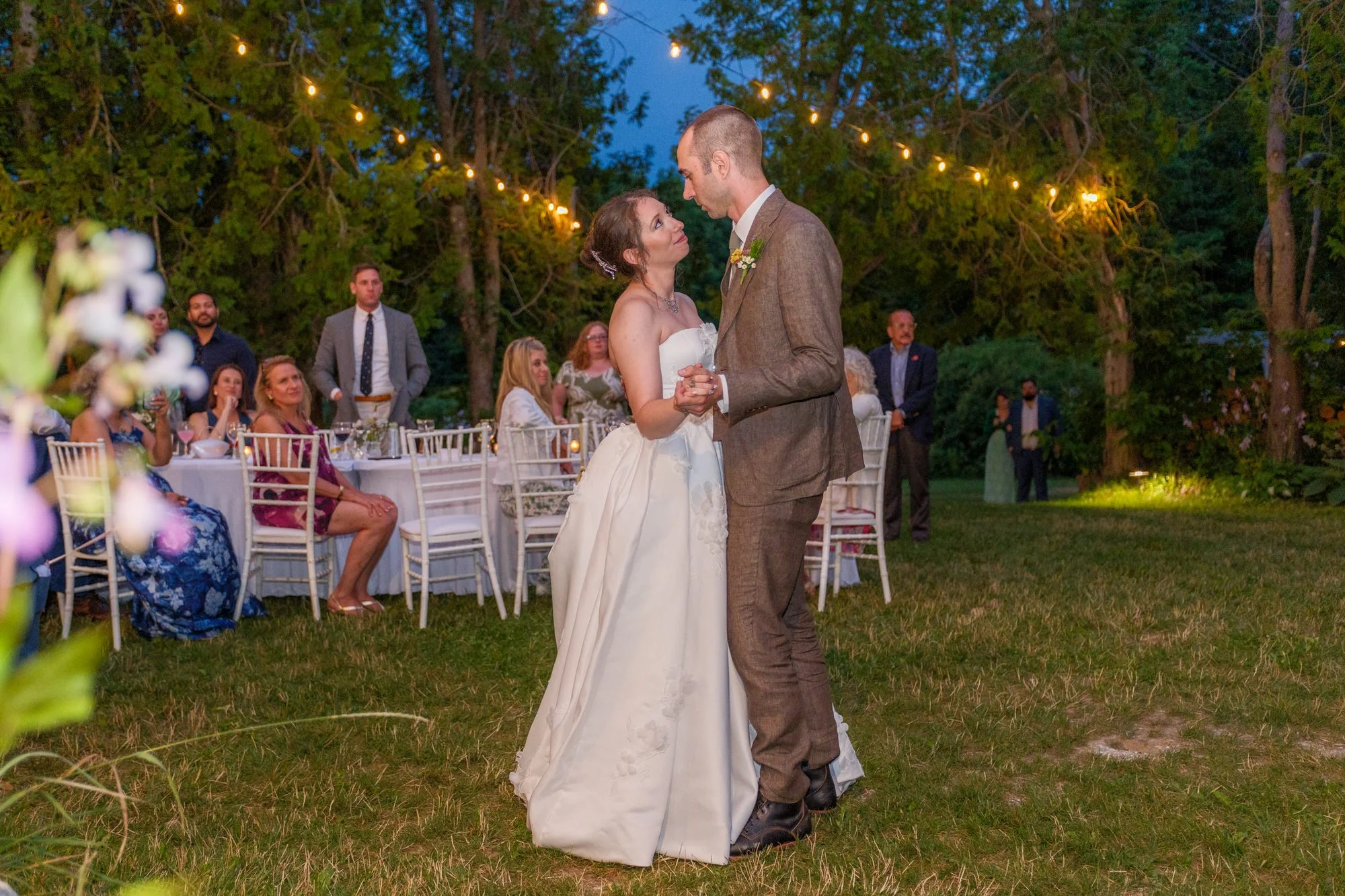 Bride and groom dancing outdoors beneath string lights