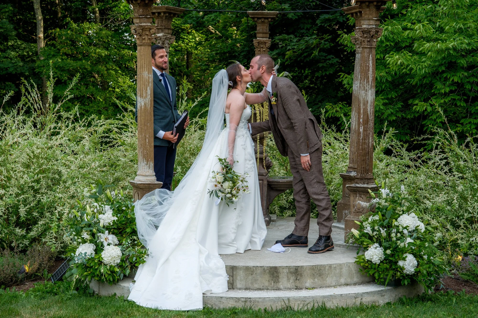 Bride and groom kissing beneath the garden arbor