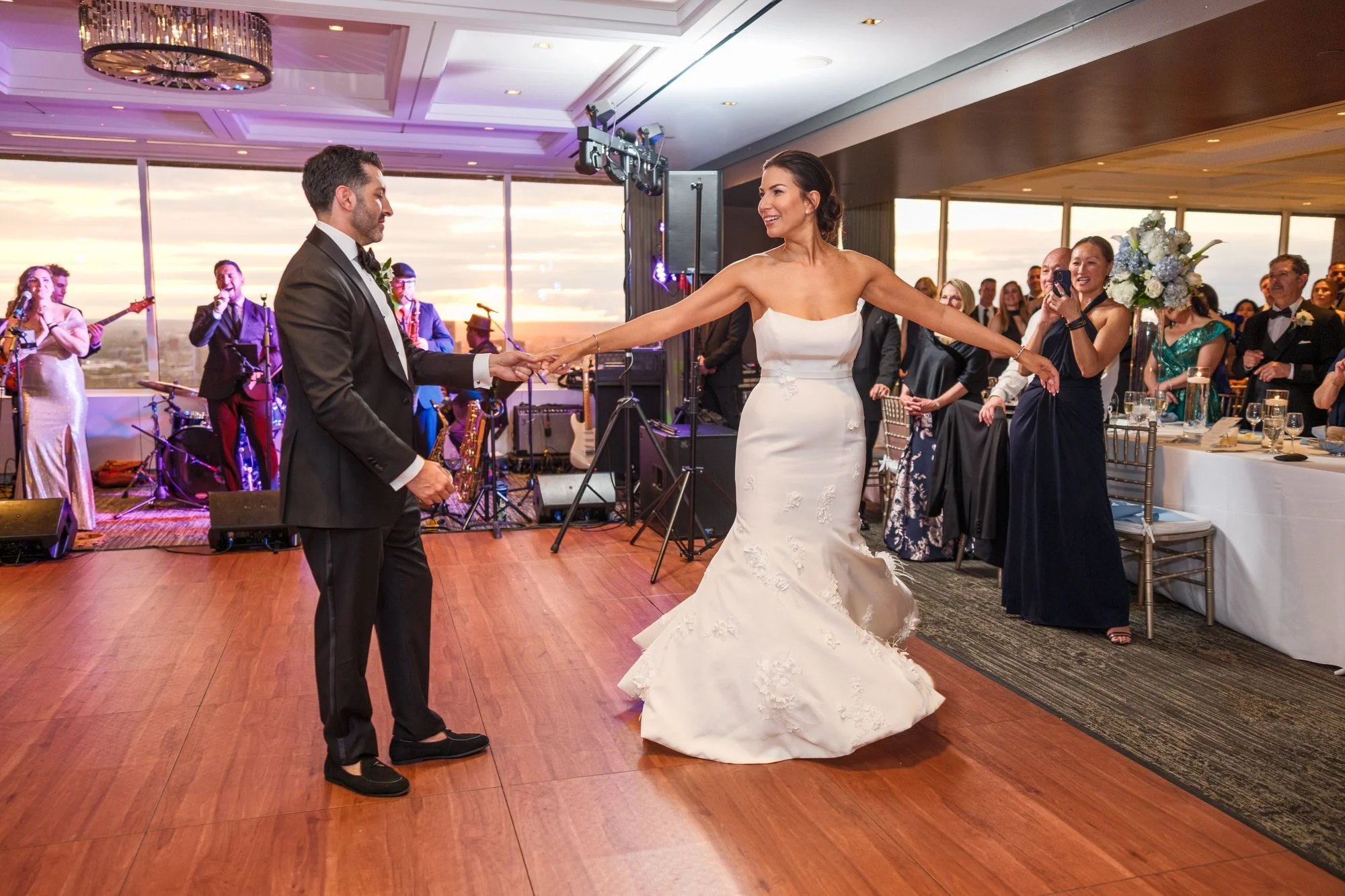 Bride spinning during the first dance at the UMass Club Boston wedding reception with live band and guests watching
