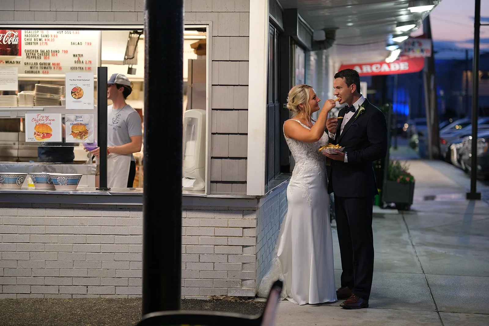 Bride and groom grabbing clams from a Salisbury Beach seafood stand after their wedding at Blue Ocean Event Center