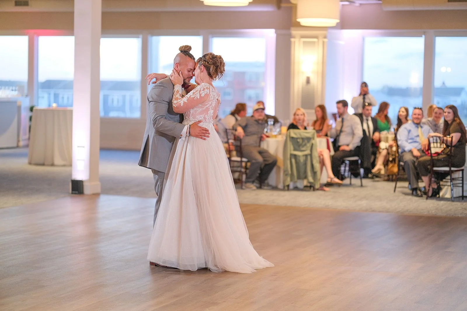 Bride and groom sharing their first dance in the Blue Ocean Event Center ballroom with ocean light coming through floor-to-ceiling windows