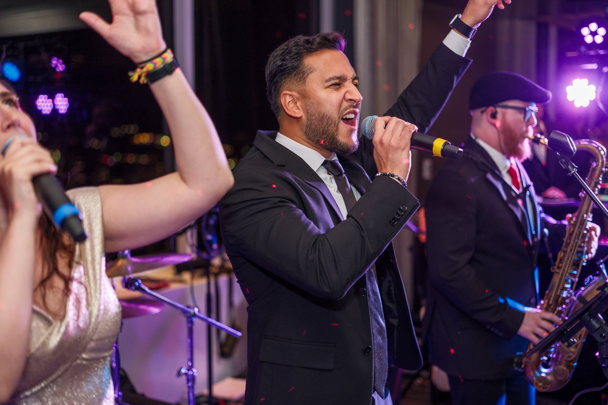 Male vocalist performing energetically with the live wedding band at the UMass Club Boston reception