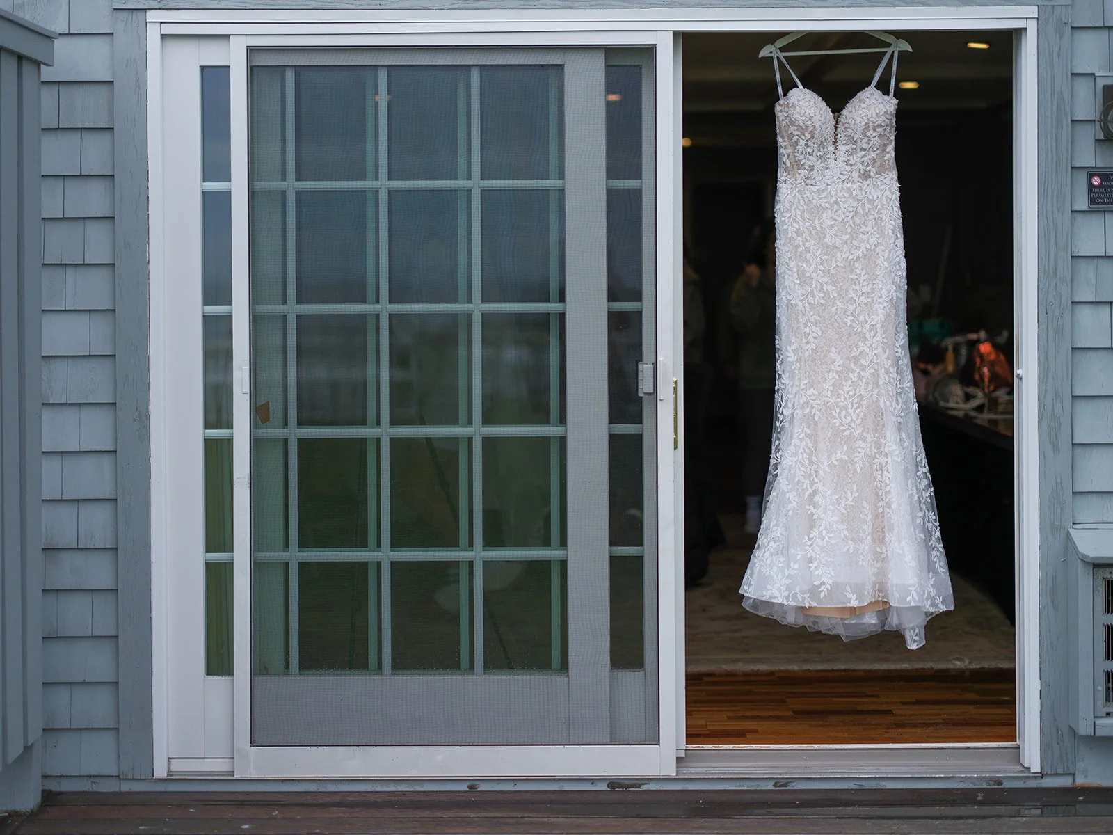 Lace wedding gown hanging in doorway of Stage Neck Inn bridal suite in York Maine