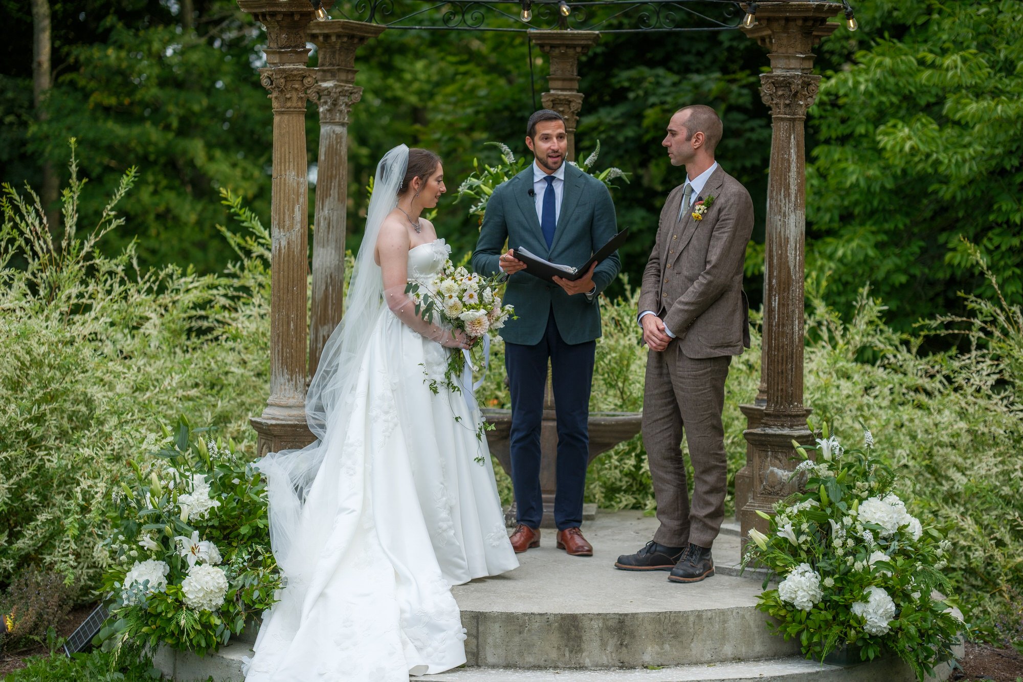 Outdoor wedding ceremony under a wooden garden arbor