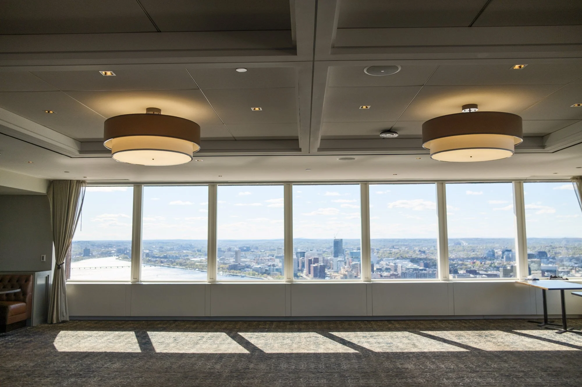 Floor-to-ceiling windows in the UMass Club's private event room offer a sweeping panoramic view of the Boston skyline and Charles River on a sunny spring afternoon