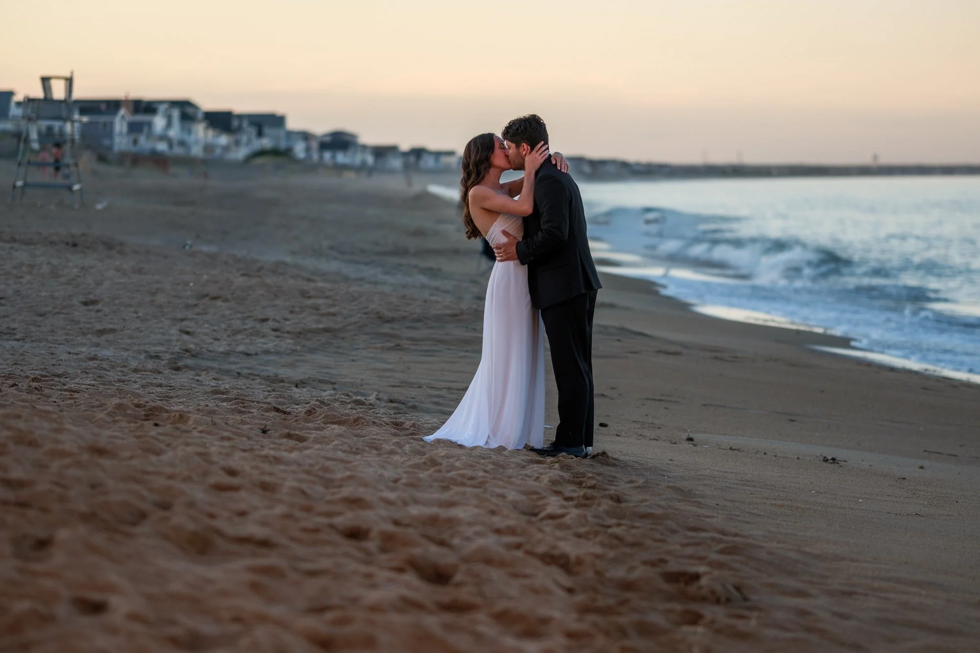 Bride and groom kissing on Salisbury Beach at sunset after their Blue Ocean Event Center wedding.