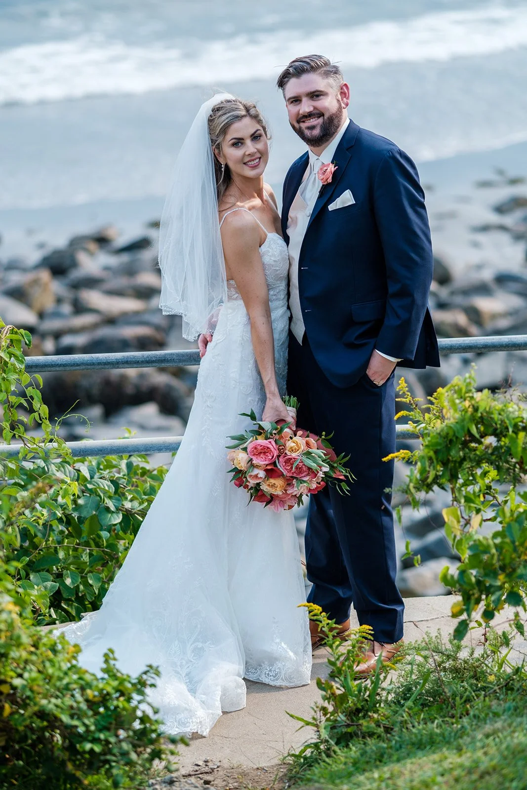 Bride and groom portrait on a rocky pathway with York Maine surf and coastline behind them