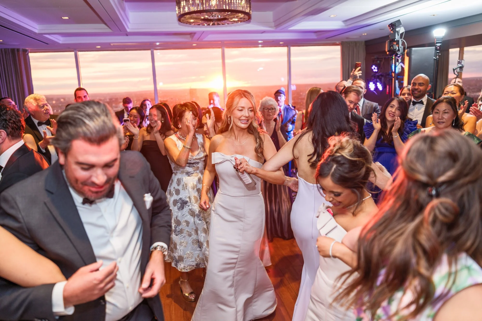 Energetic guests dancing on the floor at the UMass Club Boston wedding reception during sunset