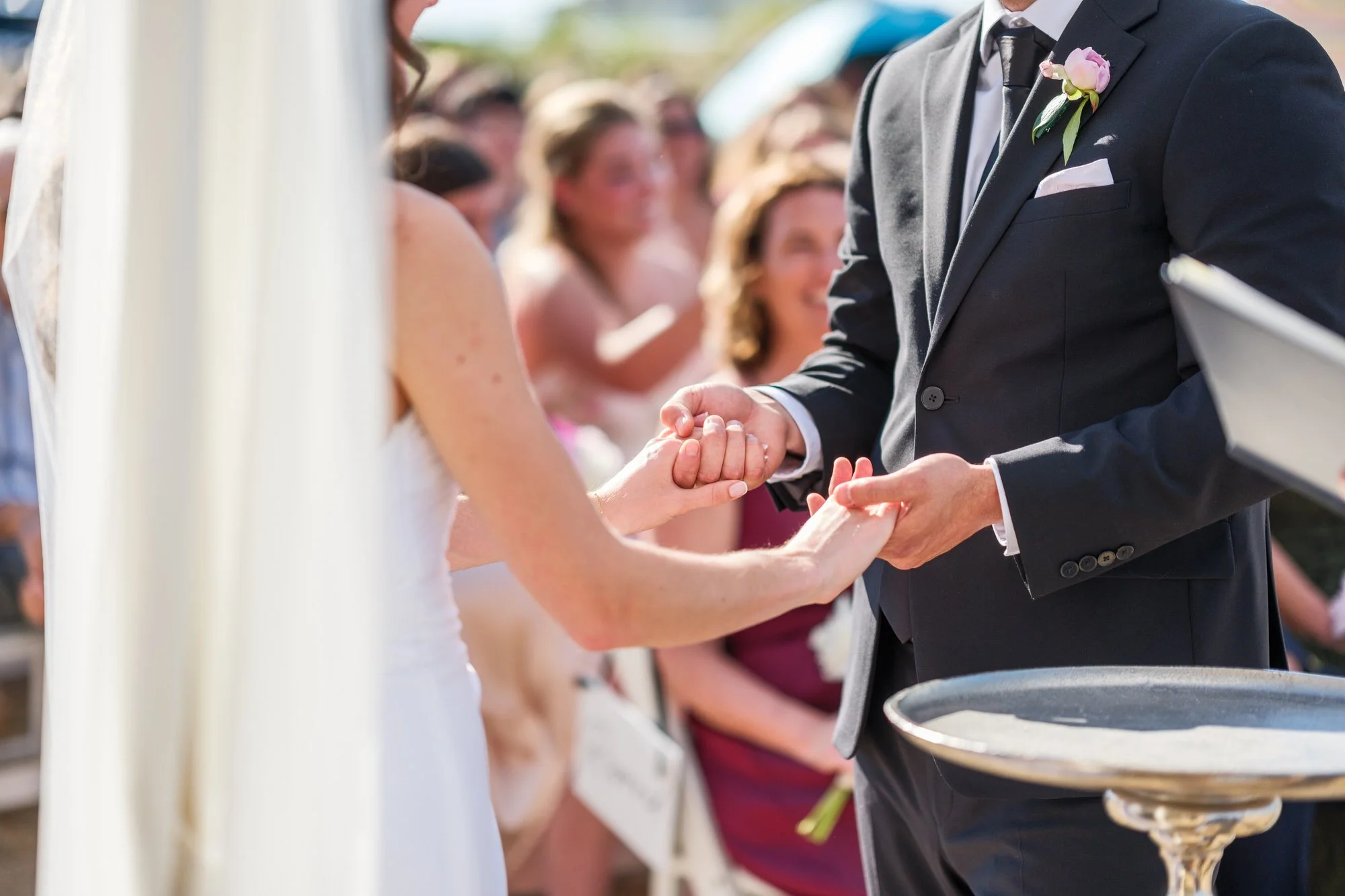Bride and groom exchanging rings during their beach ceremony at Blue Ocean Event Center.