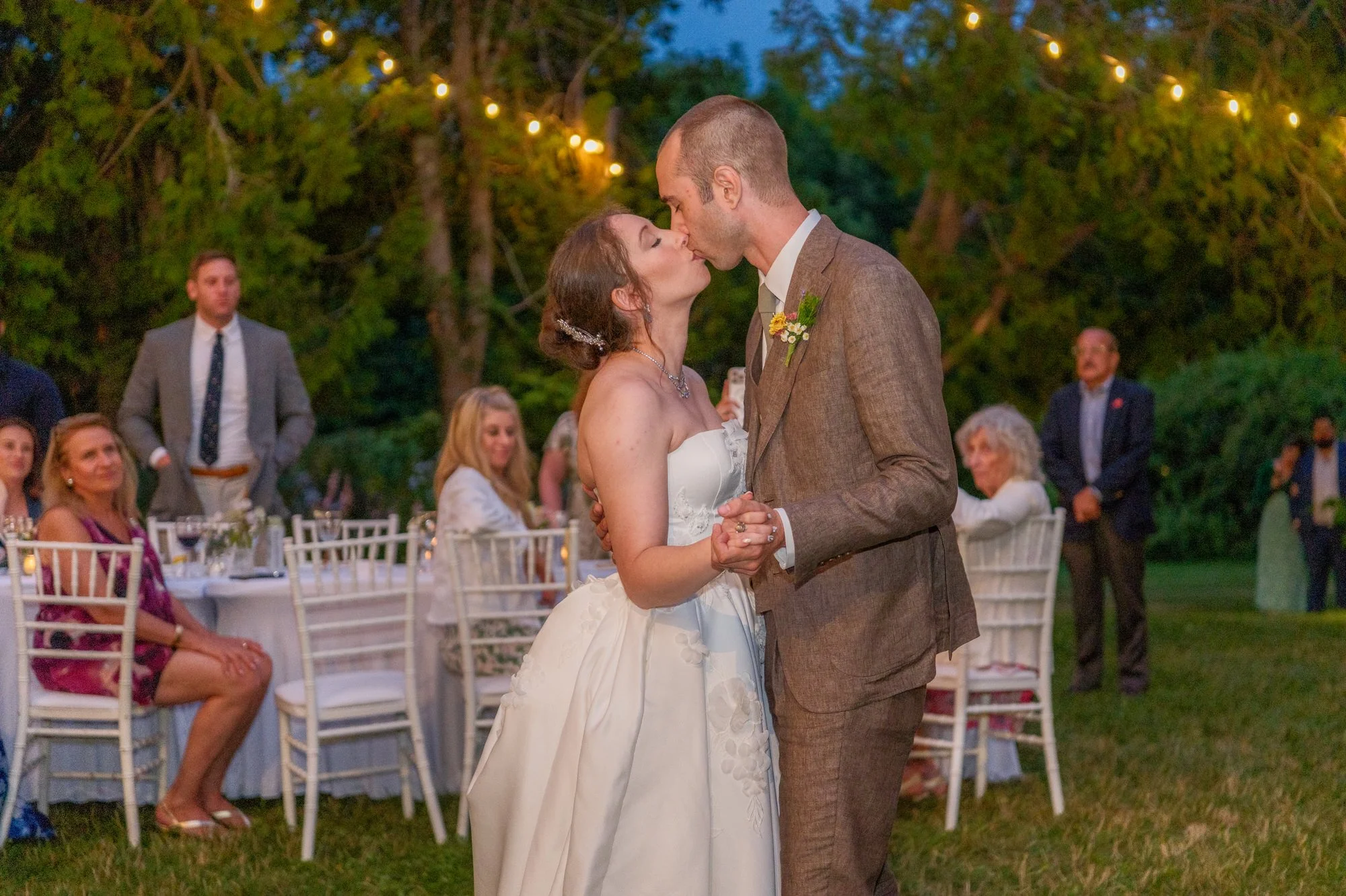 Newlyweds kissing during their evening outdoor reception