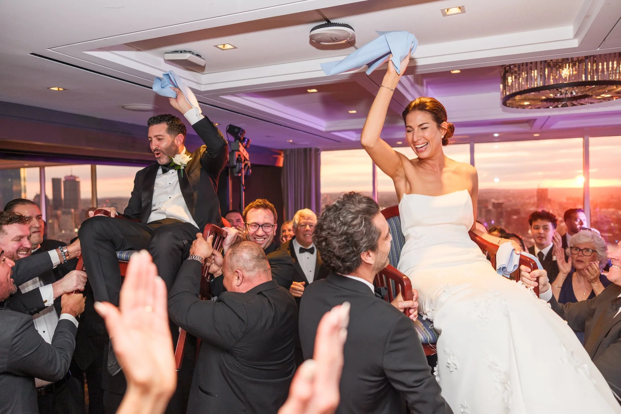 Bride and Groom lifted during the chair dance at sunset at the UMass Club in Boston