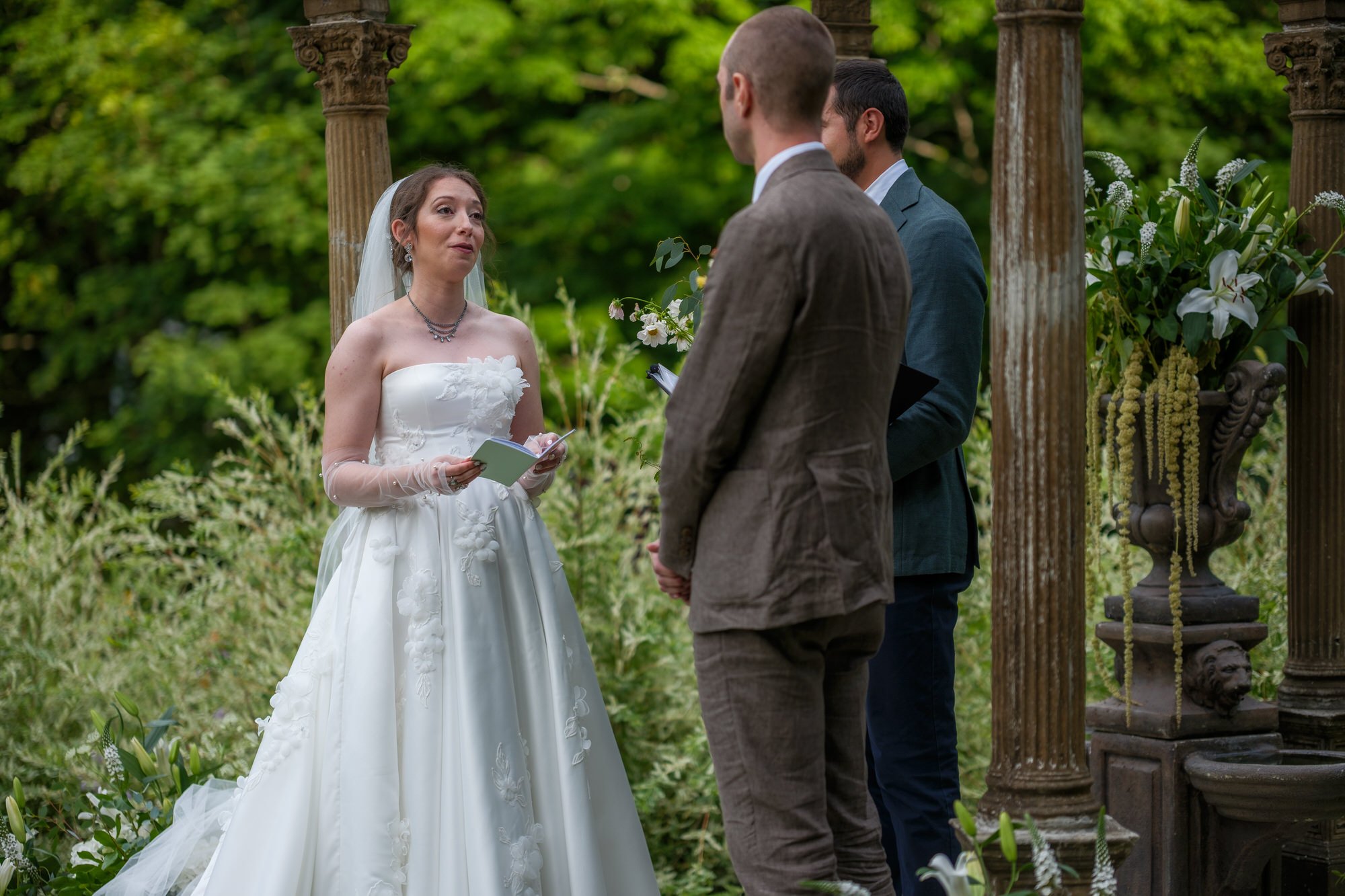 Bride and groom exchanging vows beneath a garden arbor