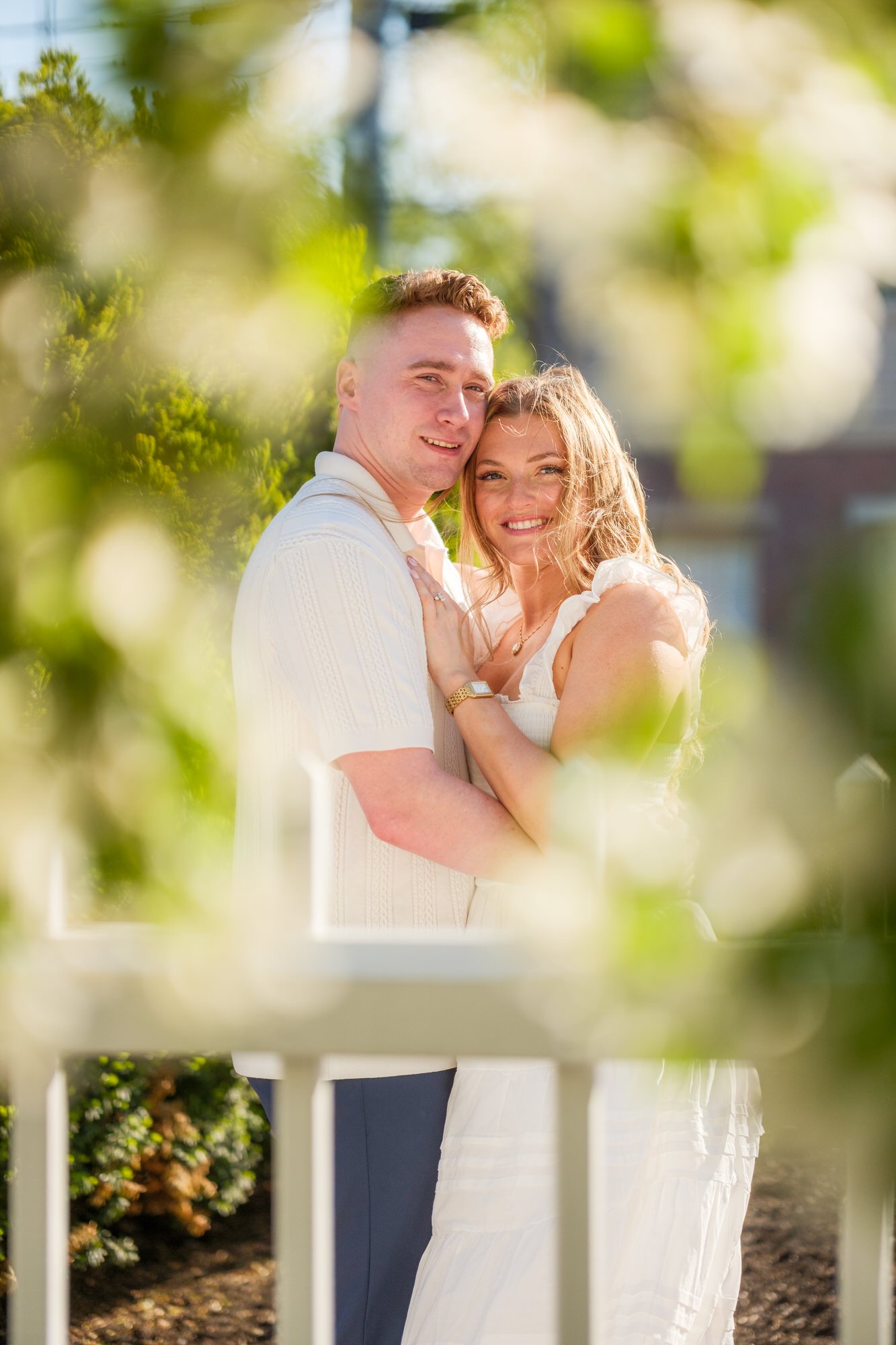 Melanie smiles at the camera as Connor gazes at her lovingly beneath blooming white tree branches at Prescott Park, Portsmouth, NH