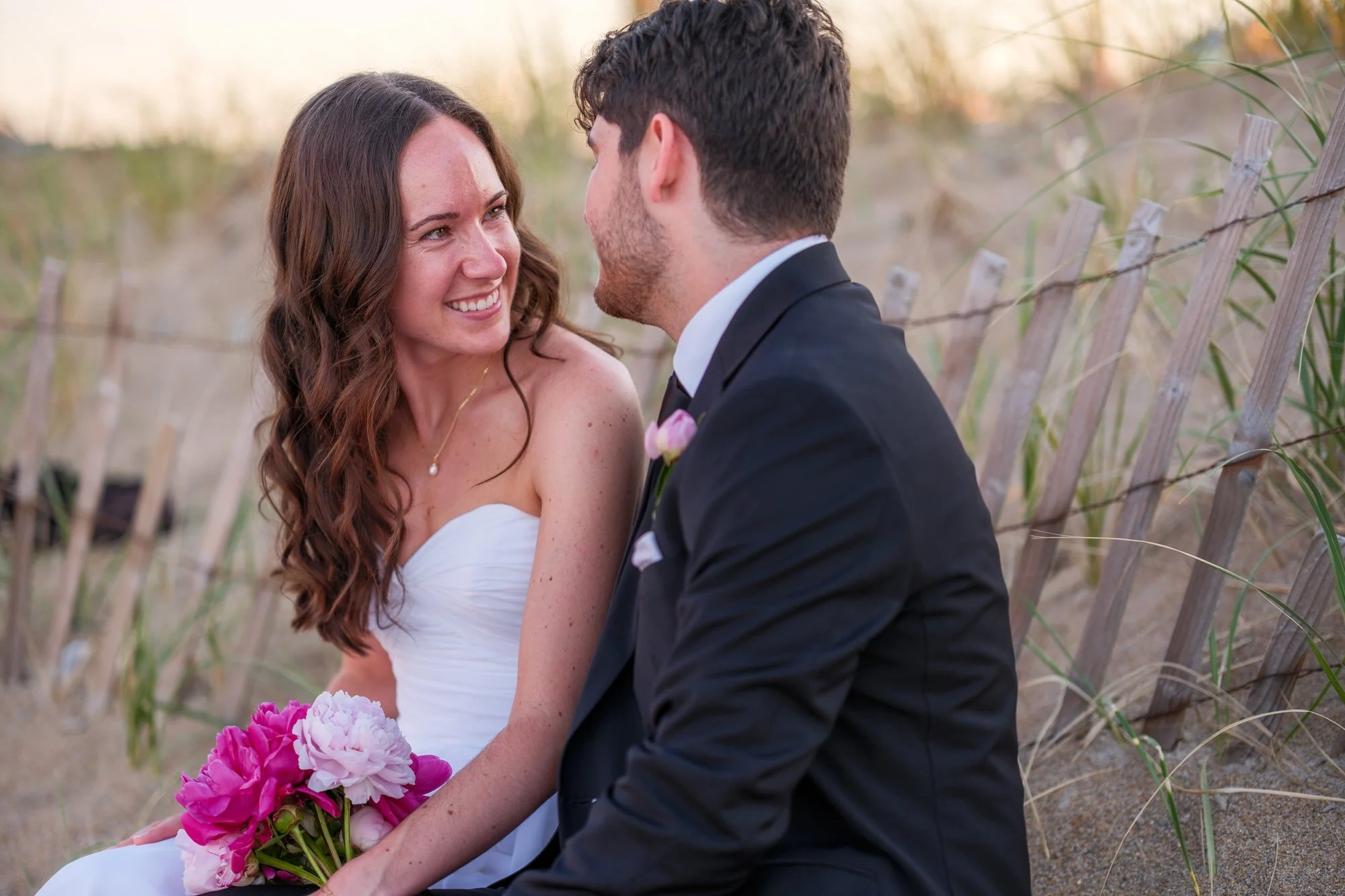 Bride smiling at the groom during a dune portrait session near Blue Ocean Event Center.