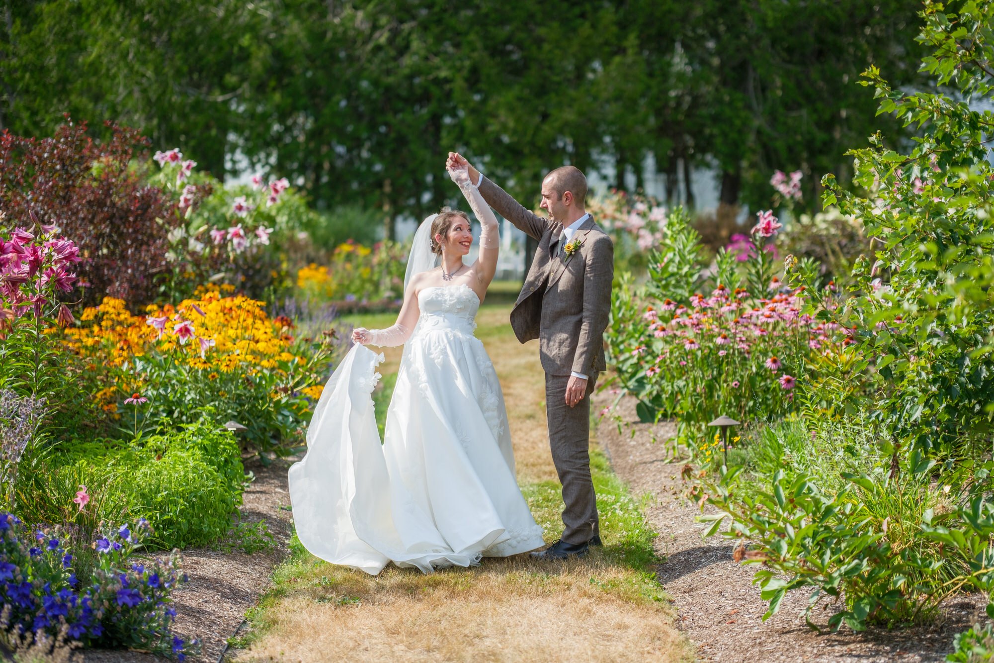 Bride and groom walking hand in hand through a colorful garden