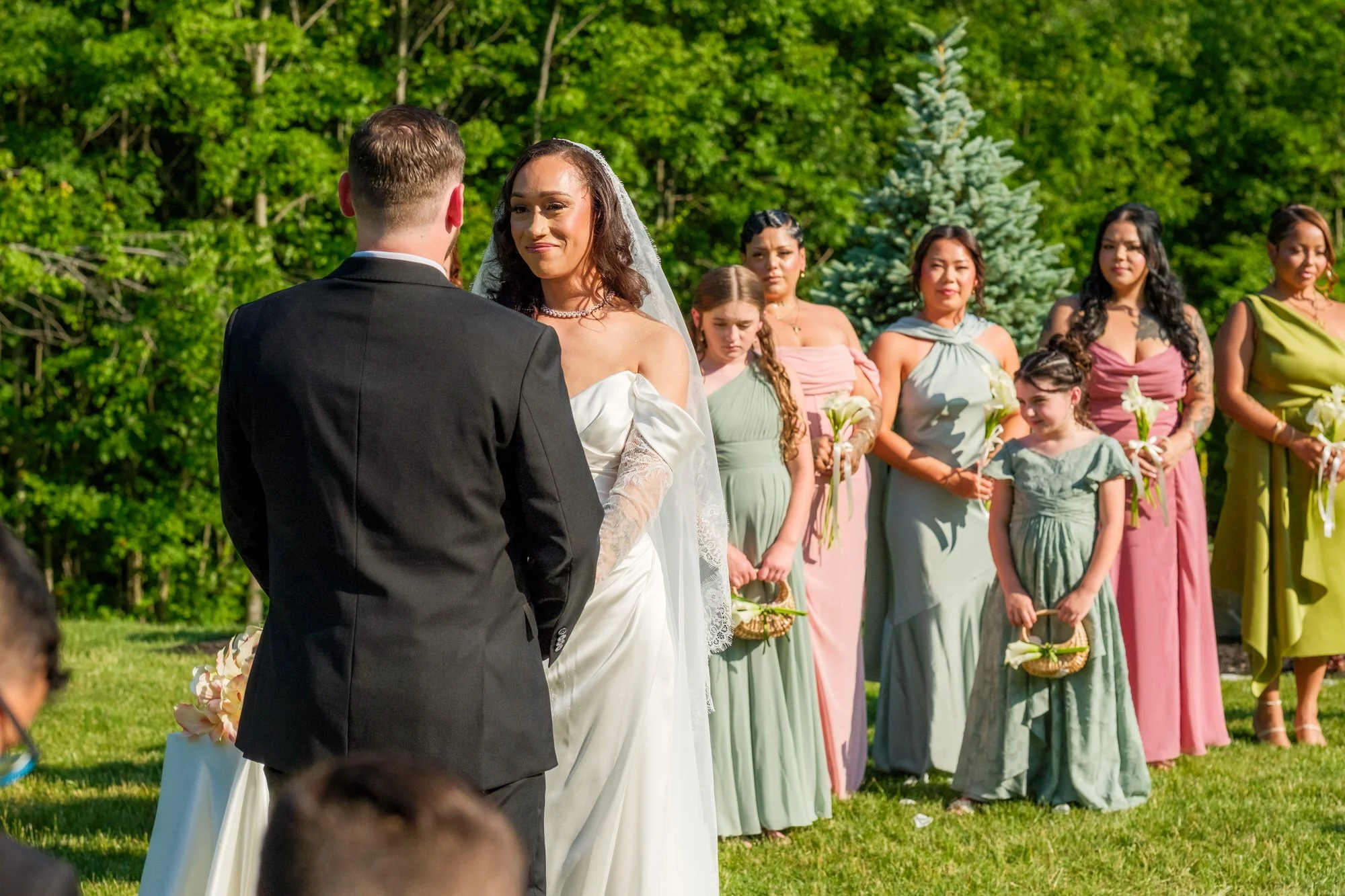 Bride and groom standing with wedding party during ceremony at Hyla Brook Estate