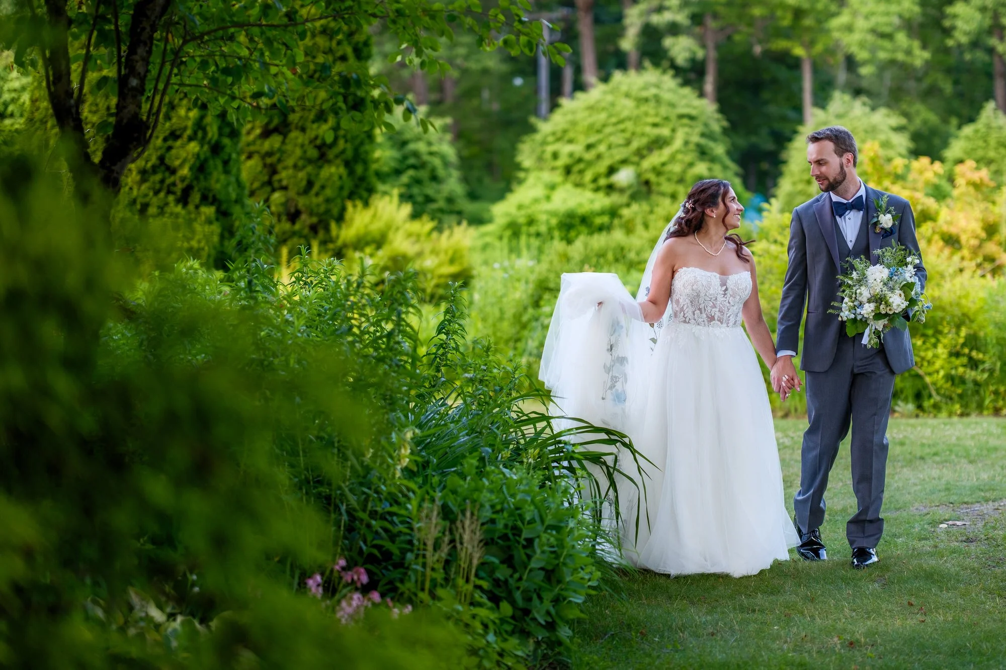 Newlyweds walk through greenery at Lake Morey Resort wedding venue in Vermont