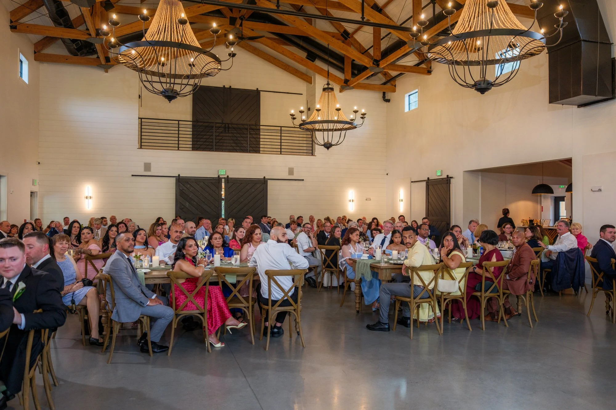 Wedding guests seated in the reception barn at Hyla Brook Estate