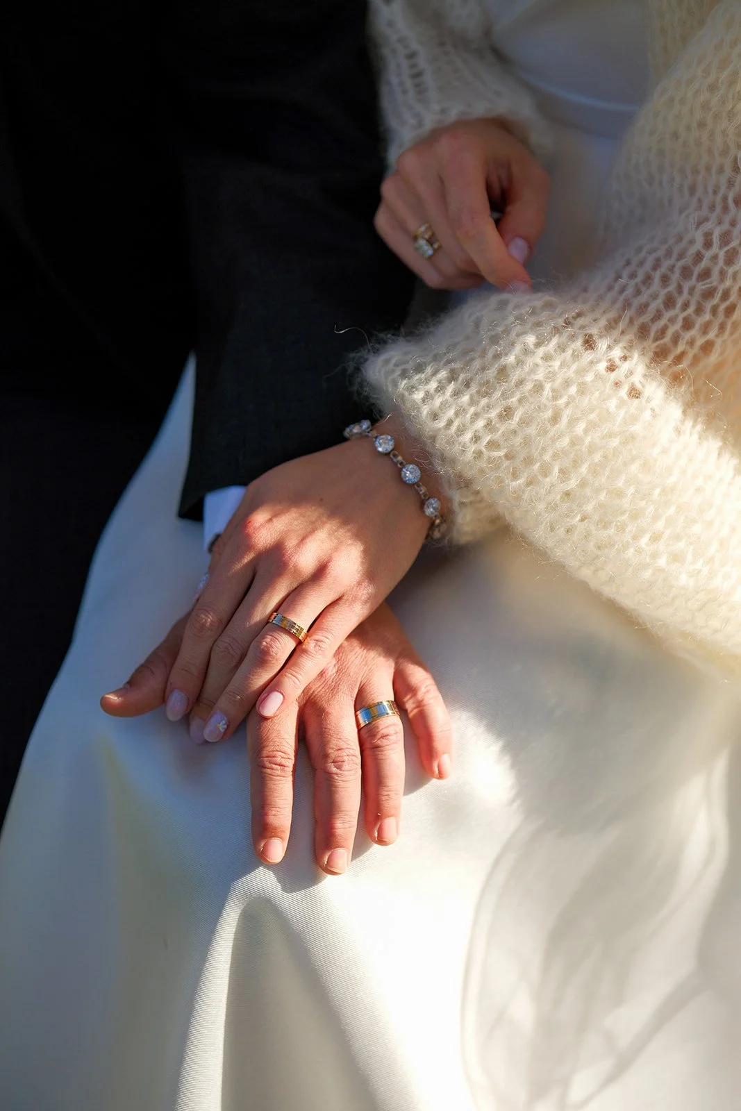 Close-up detail photo of bride and groom wedding rings on white dress at York Maine wedding