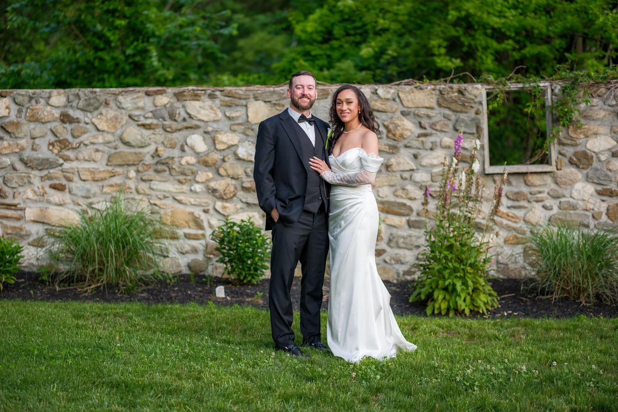 Bride and groom portrait by stone wall at Hyla Brook Estate
