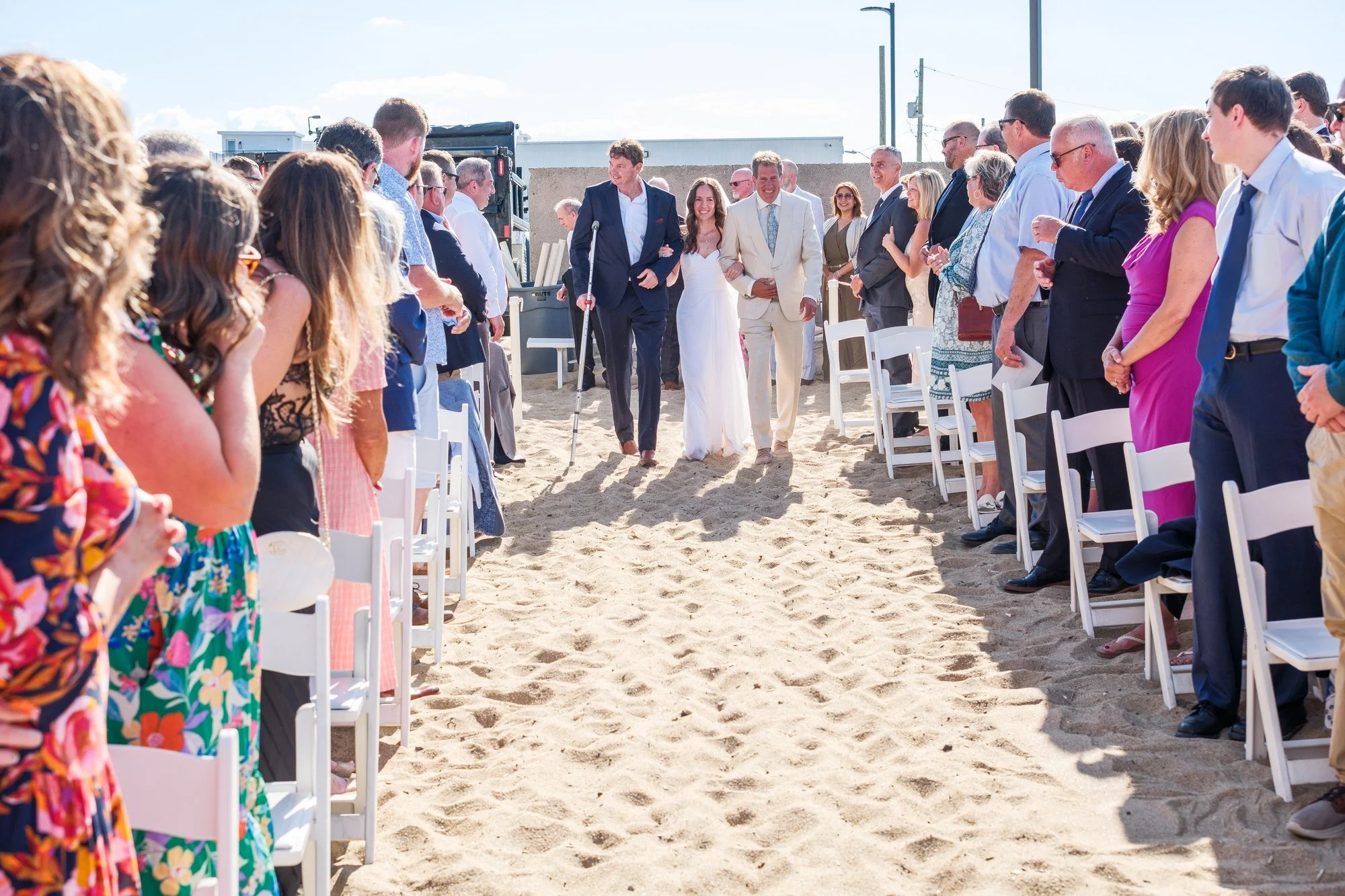 Bride escorted down the beach ceremony aisle at Blue Ocean Event Center in Salisbury, MA.