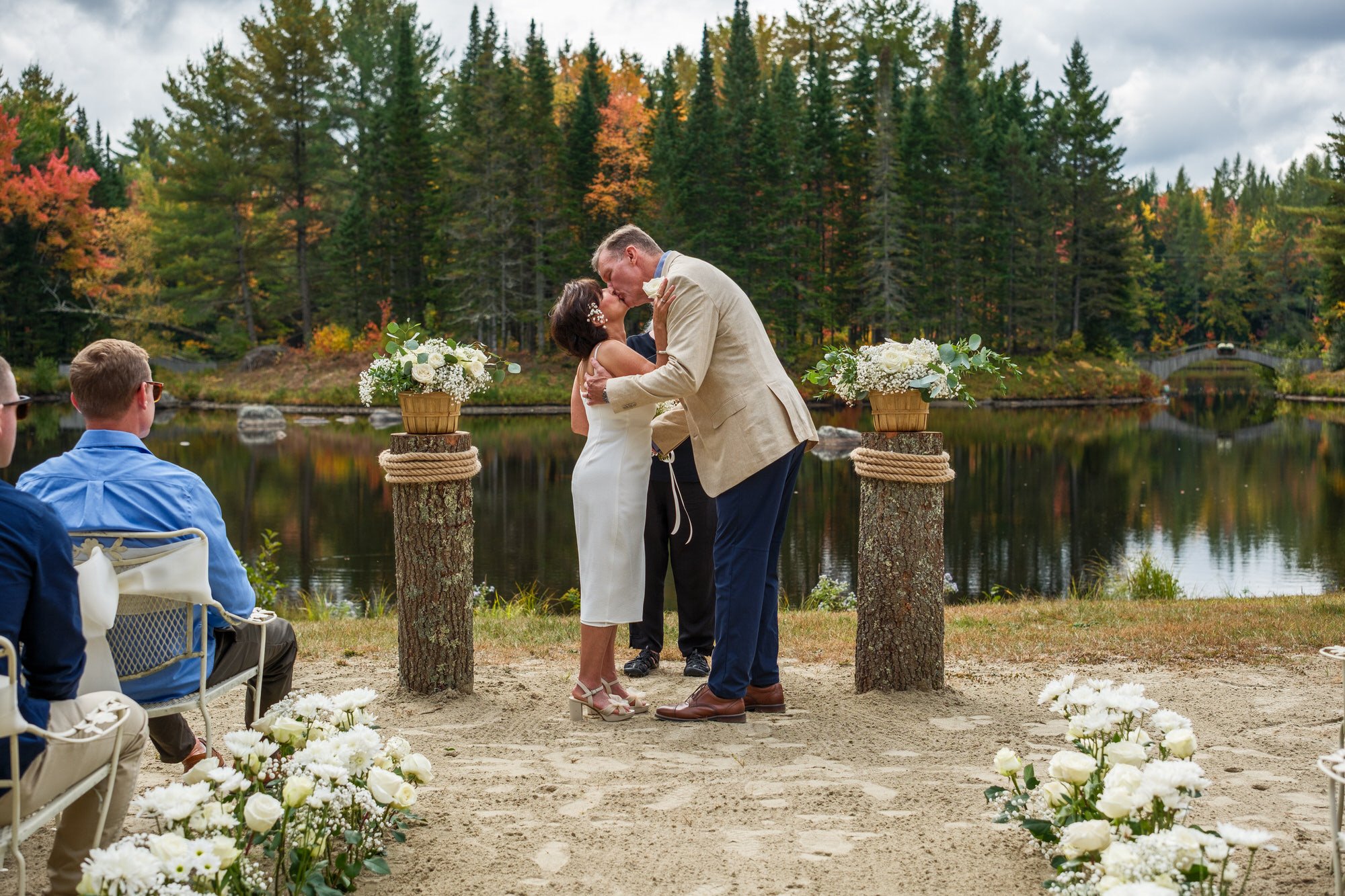 Newlyweds sharing their first kiss with the White Mountains forest in the background and lake