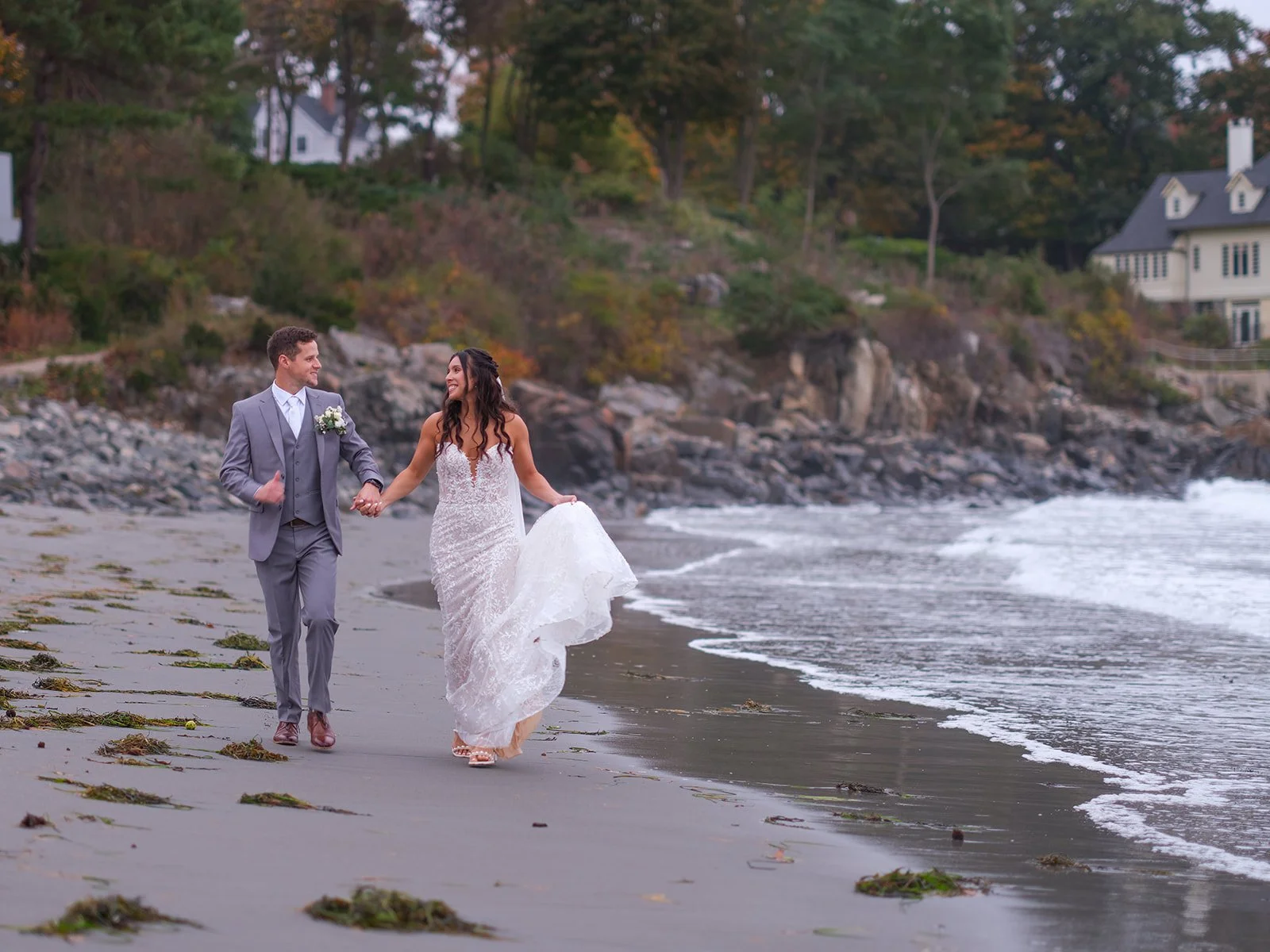 Bride and groom walking hand in hand along the York Maine beach shoreline after their wedding ceremony