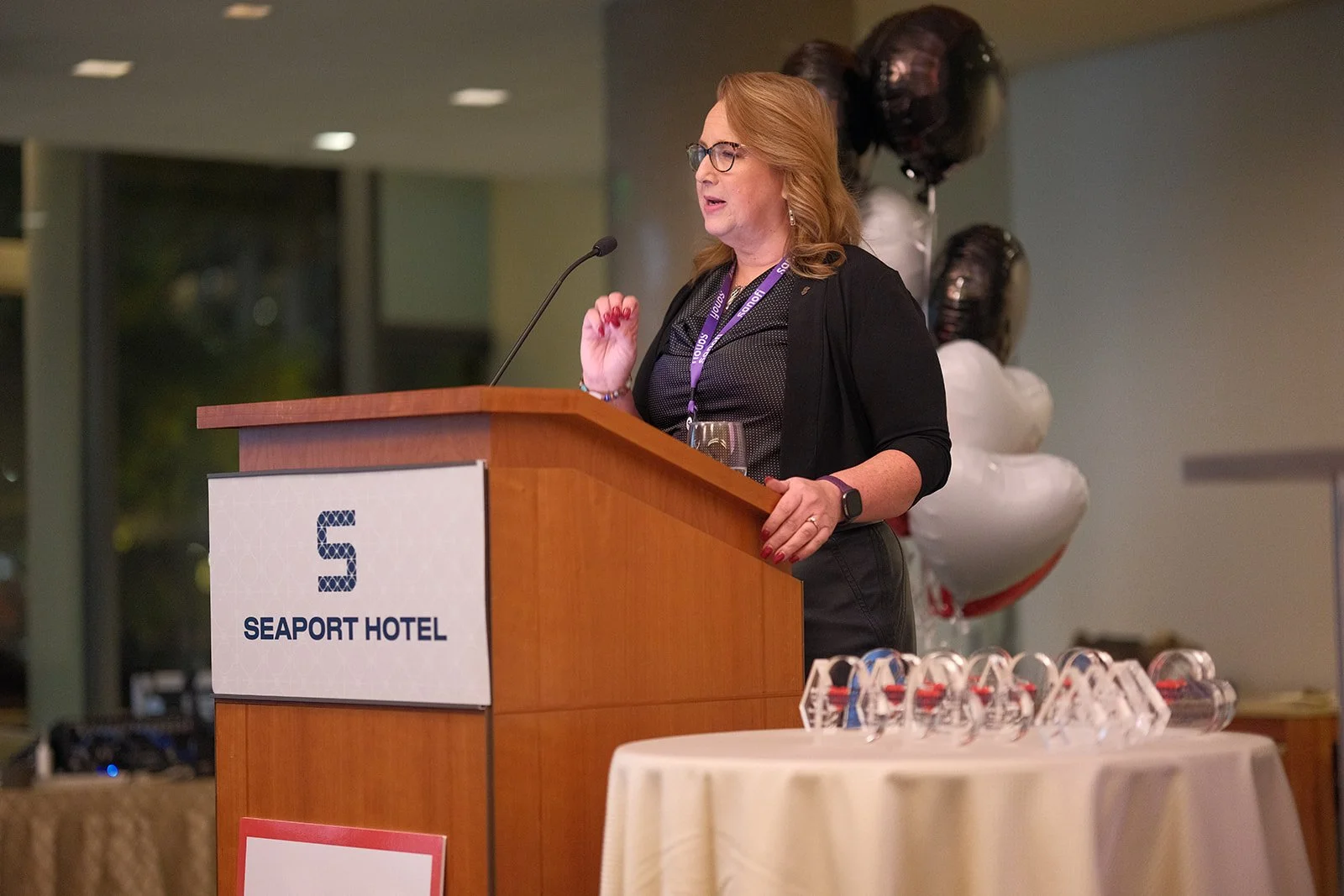 Keynote speaker gestures expressively at the HCMA 2024 Annual Patient Meeting podium at Boston Seaport Hotel