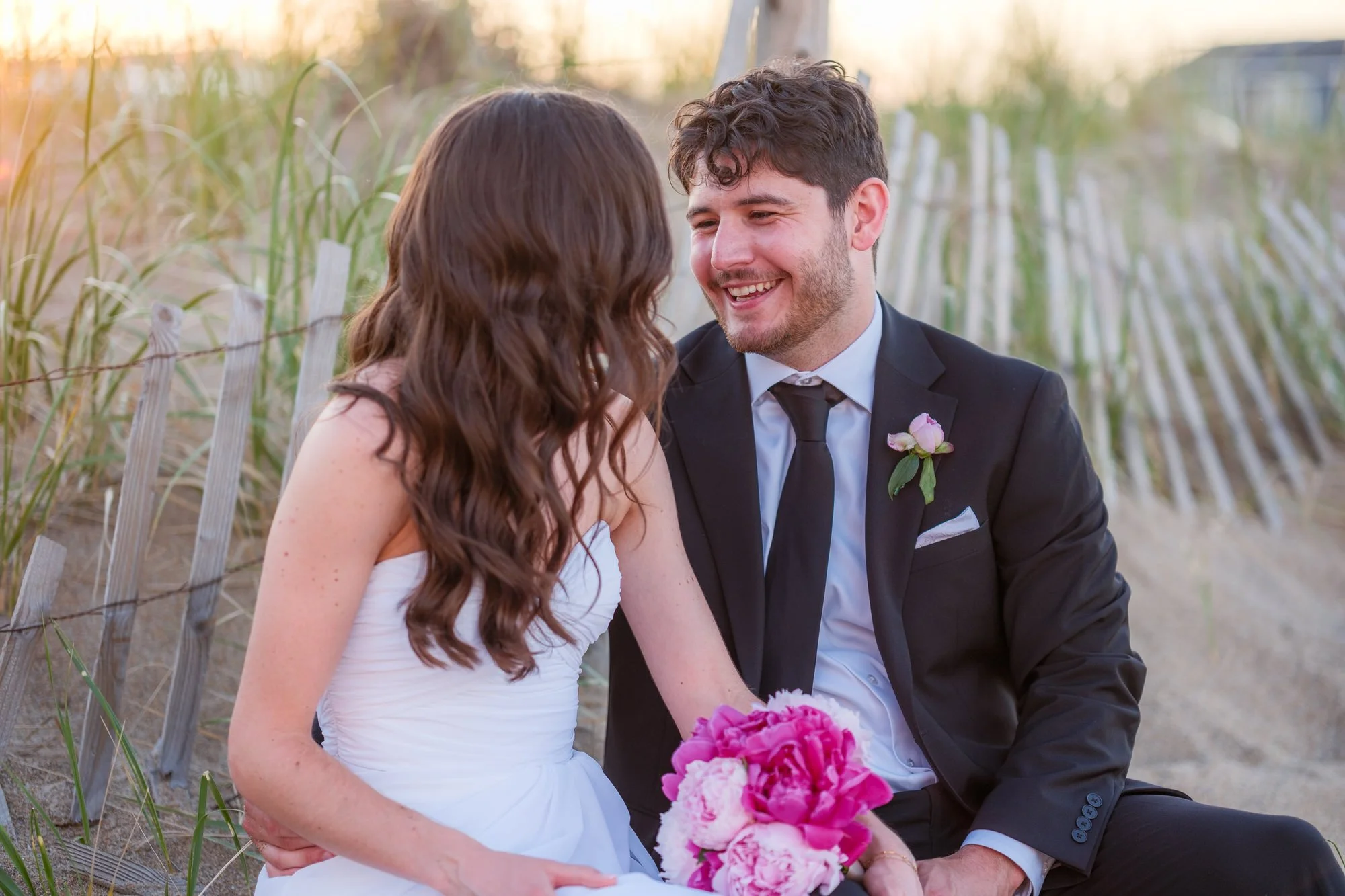 Bride and groom laughing together during sunset portraits in the Salisbury Beach dunes.