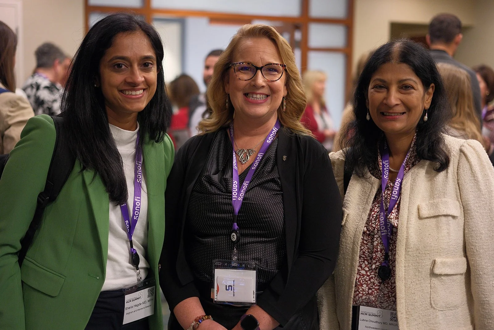 Three physicians wearing Sanofi lanyards smile together during networking at the 2024 HCM Summit in Boston