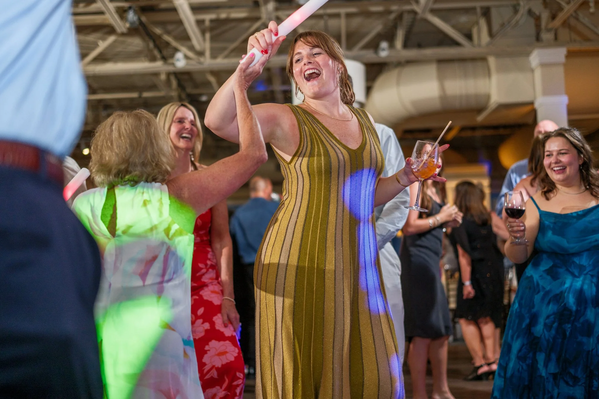 Guests dancing with drinks during a lively Blue Ocean Event Center wedding reception.