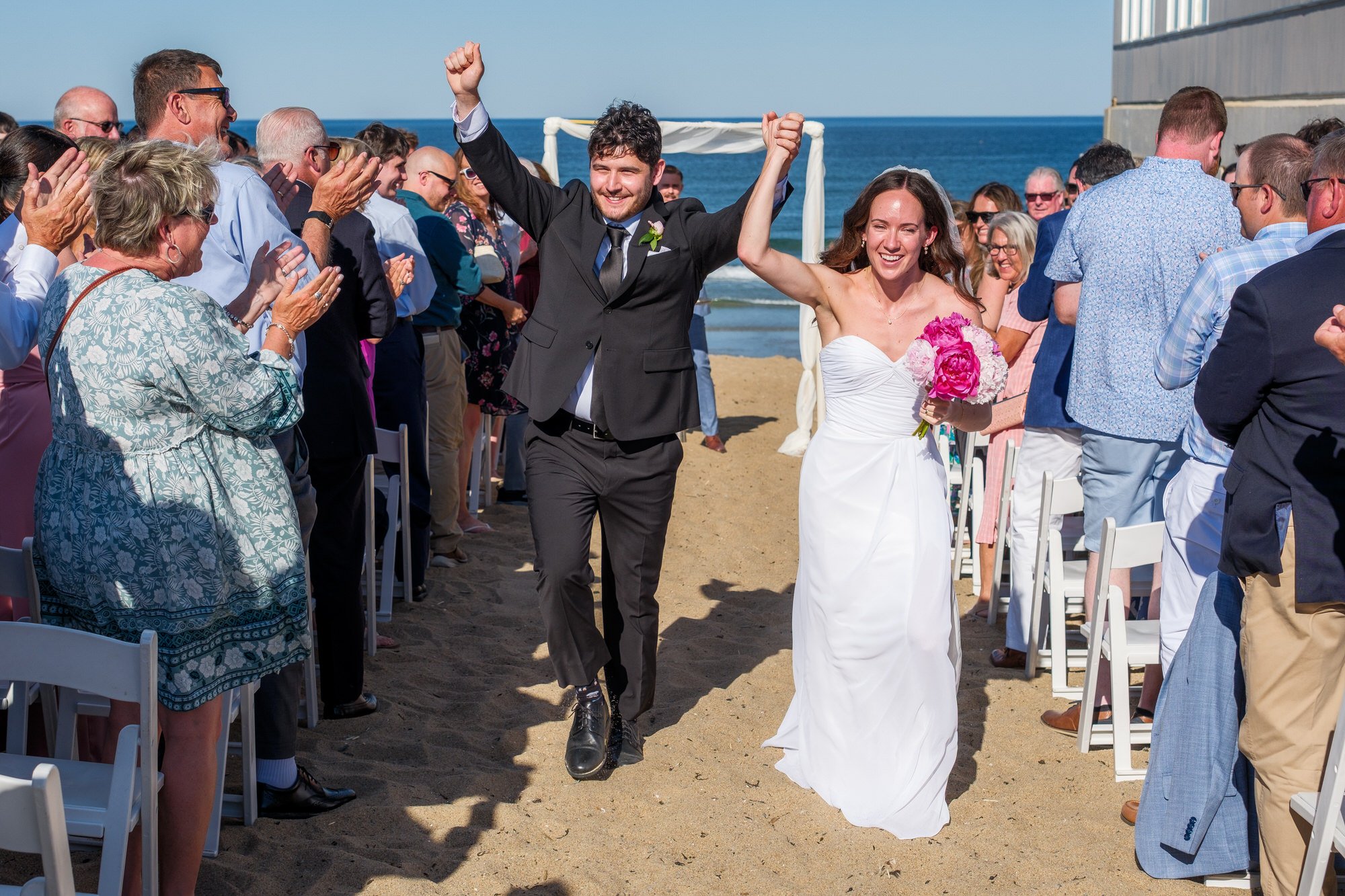 Bride and groom celebrating down the sandy aisle after their Blue Ocean Event Center ceremony.
