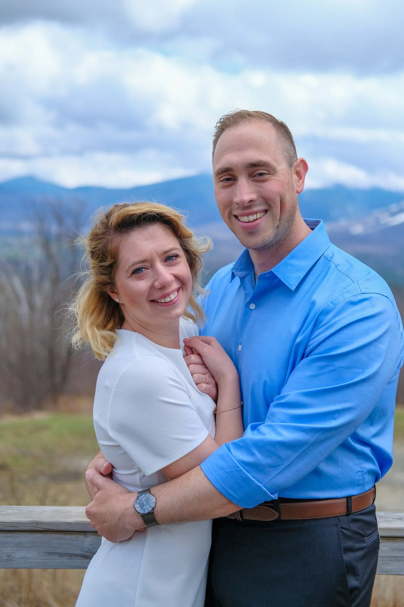 Bride and groom smiling and embracing at a scenic overlook with panoramic White Mountains views during their Franconia Notch spring elopement