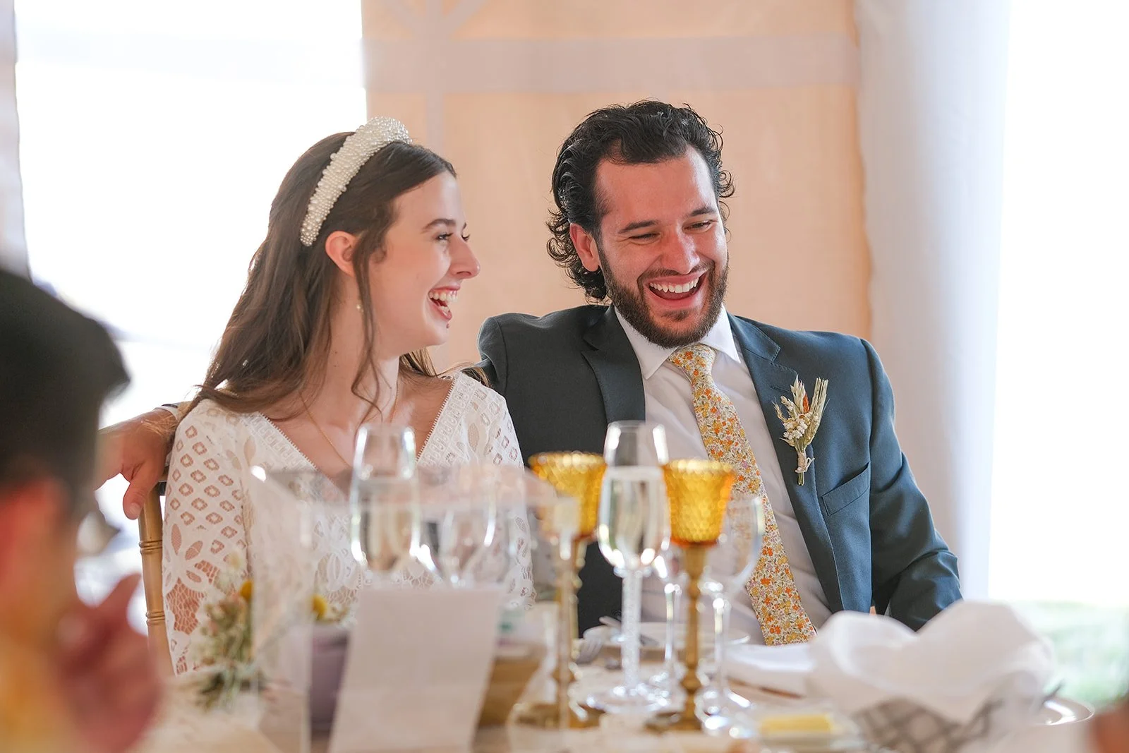 A bride and groom laughing together at their wedding reception.