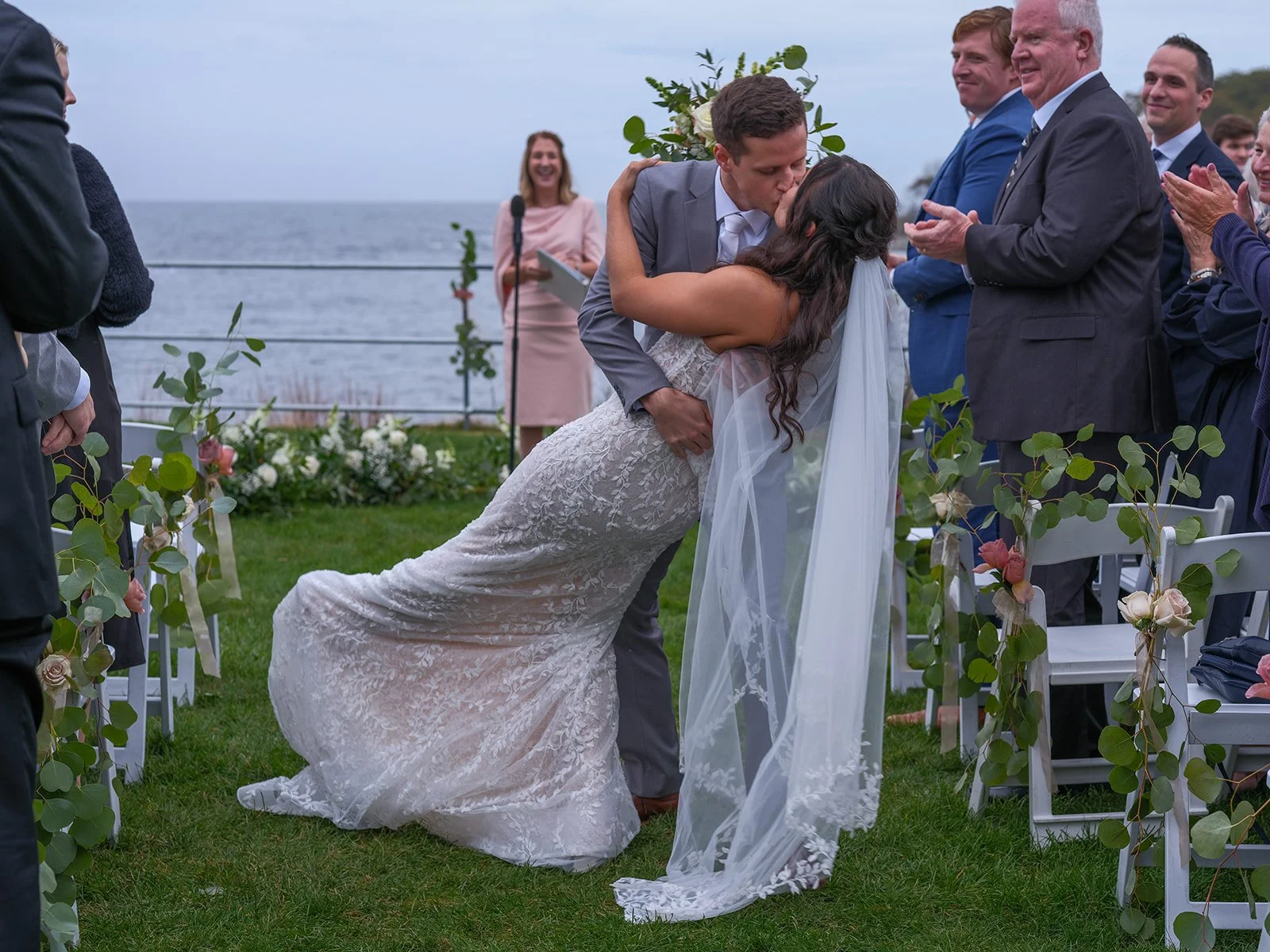Dramatic dip-kiss during first kiss at York Maine outdoor wedding ceremony surrounded by applauding guests