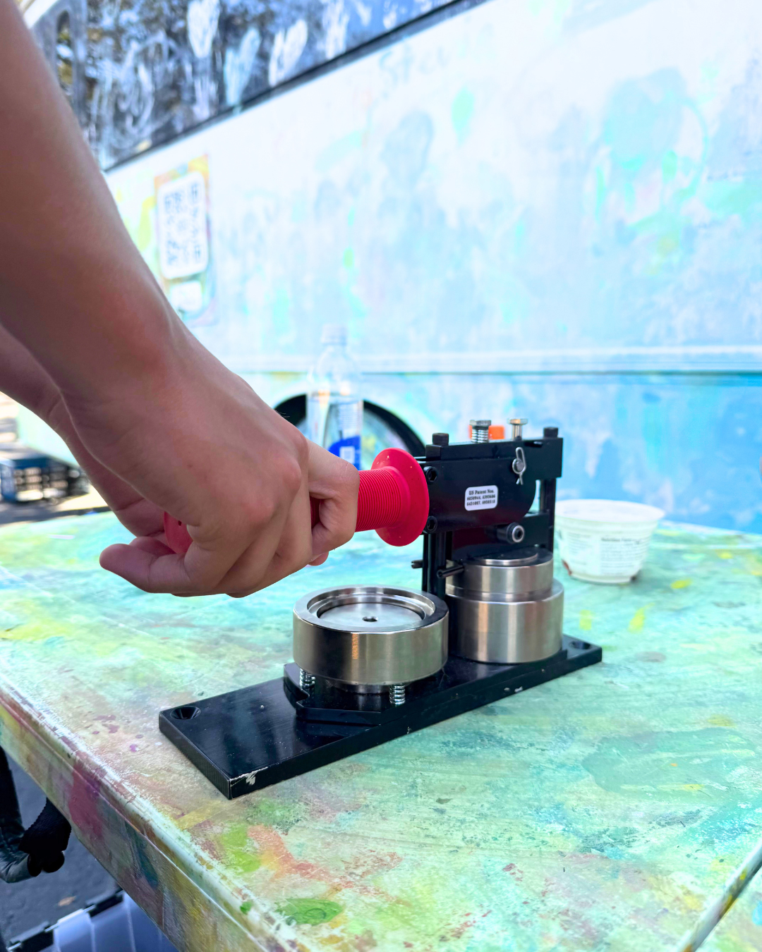 Hands of a child pressing down on the handle of a button maker.