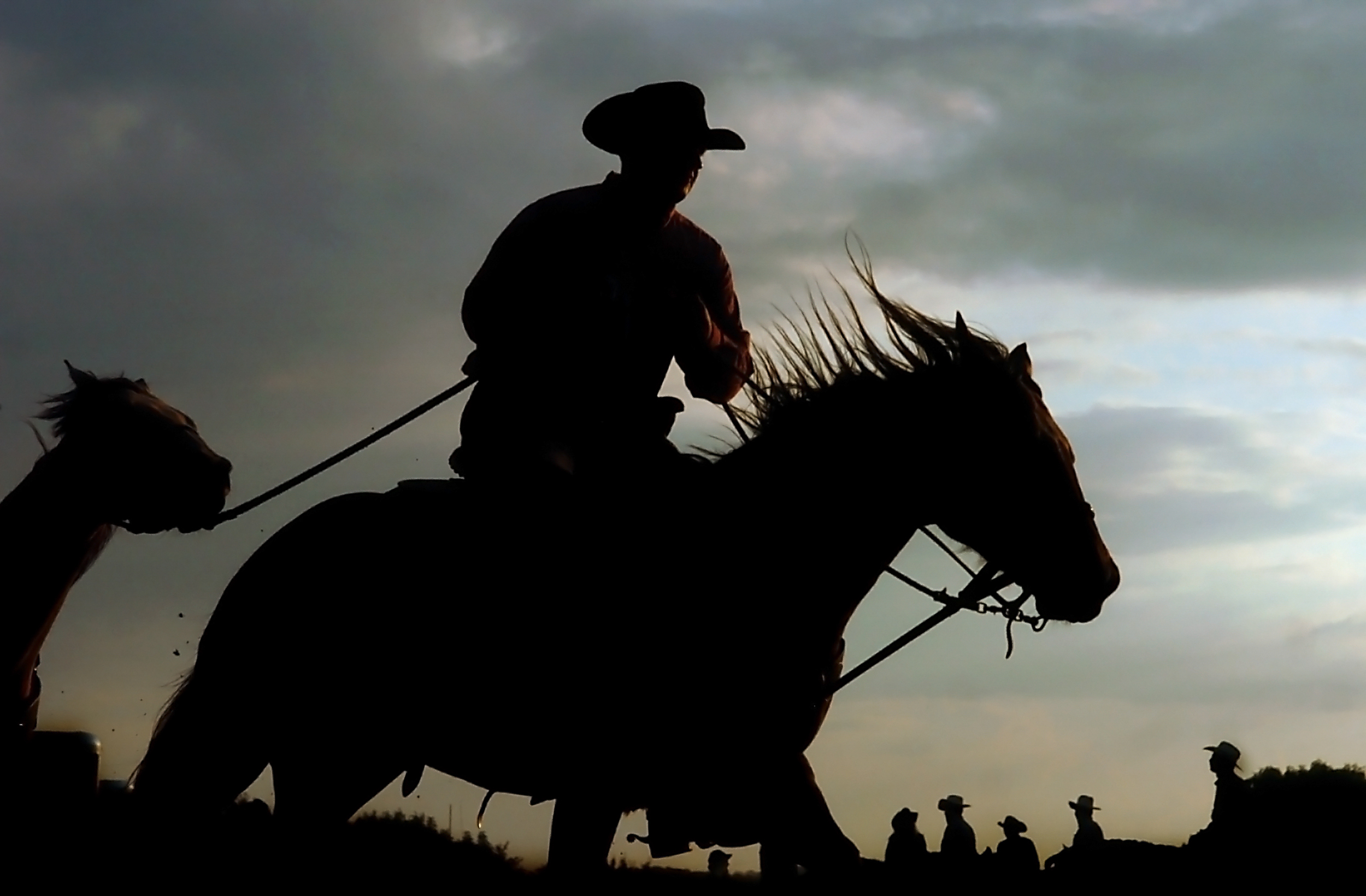 A cowboy warms up his horse in the paddock as the sun begins to set before the start of the Fort Armstrong Championship Rodeo at Crooked Creek Horse Park in Ford City, Pa.